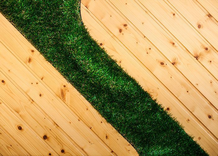 A wooden floor with a green stripe of grass on it.
