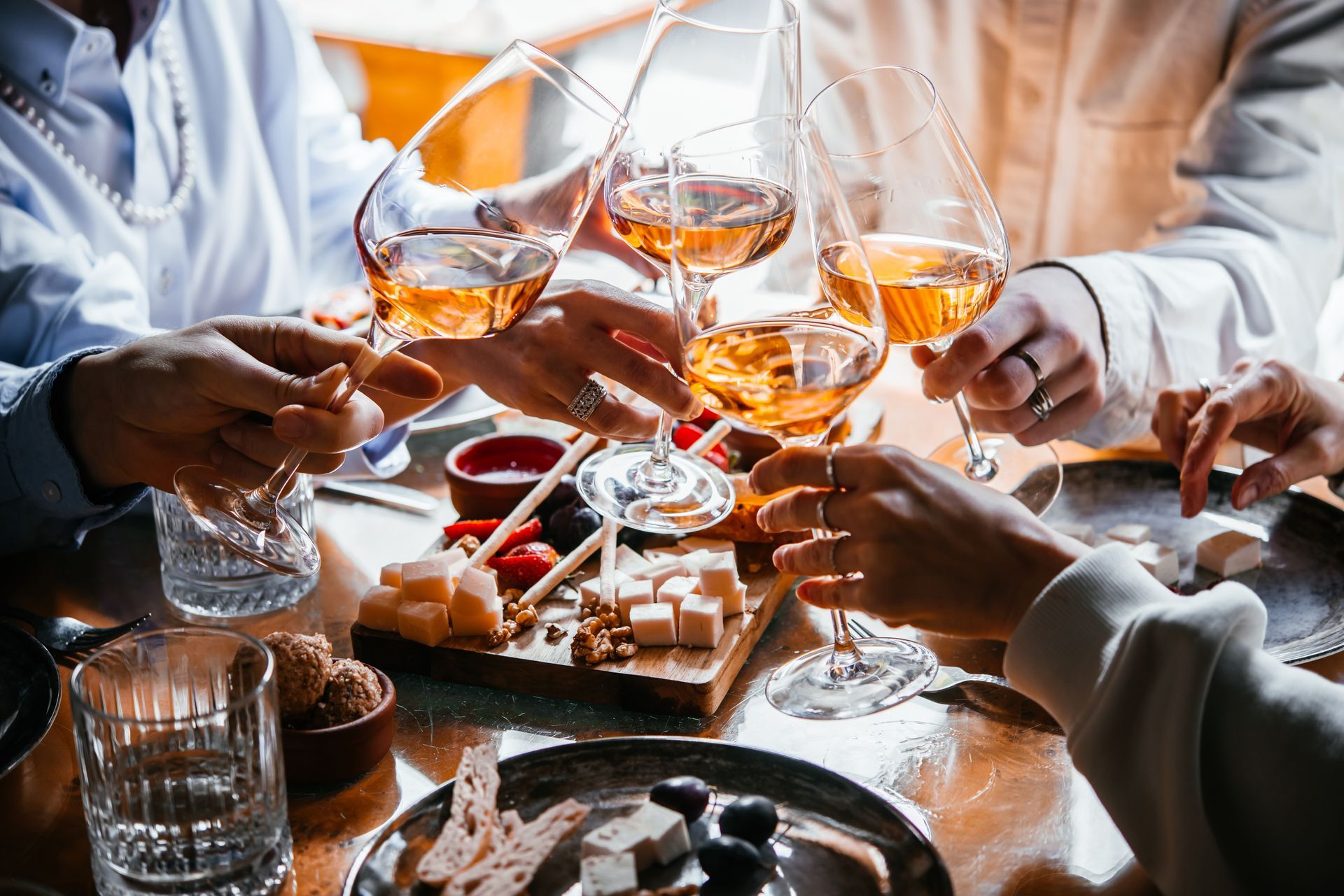 A group of people are sitting at a table toasting with wine glasses.