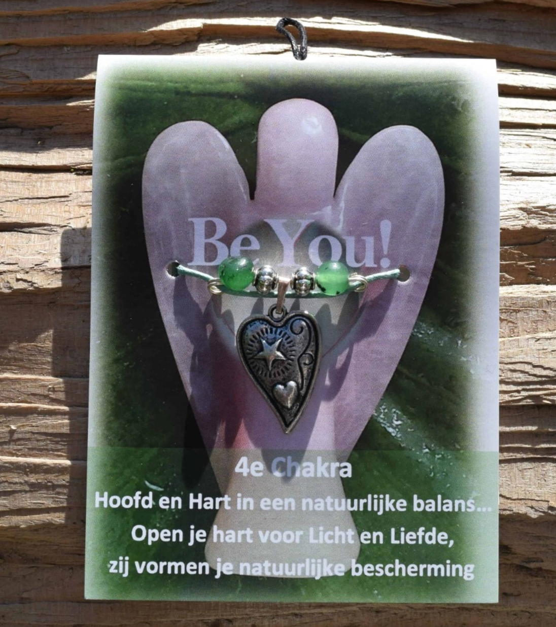 Een engelvormig kaartje met een bedeltje, groene kralen en de tekst: