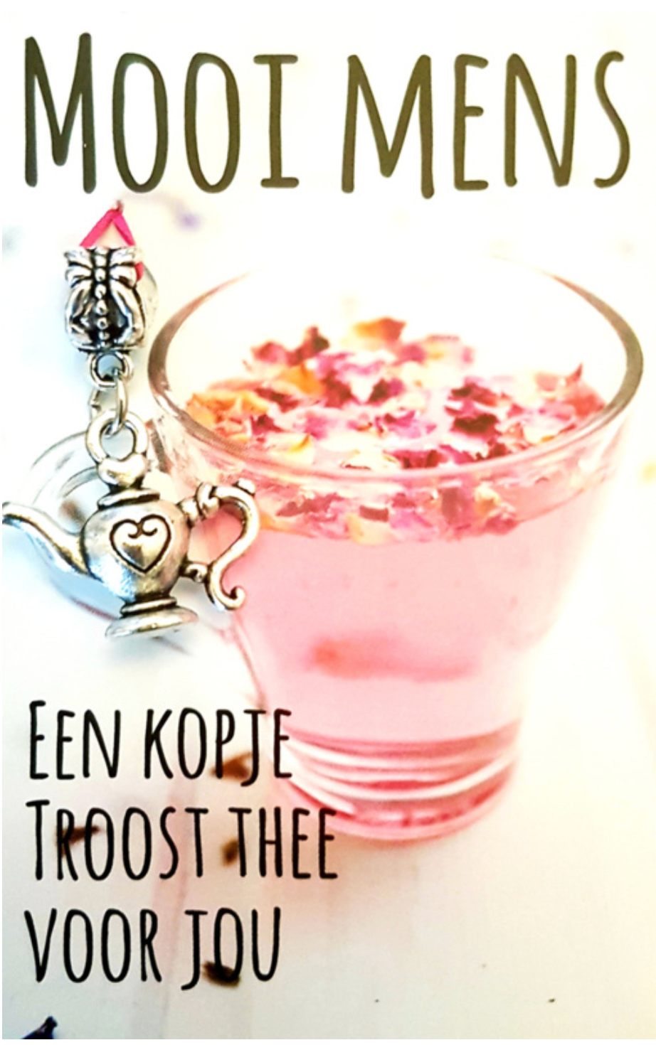 Pink tea in a clear glass with flower petals, next to a teapot charm.