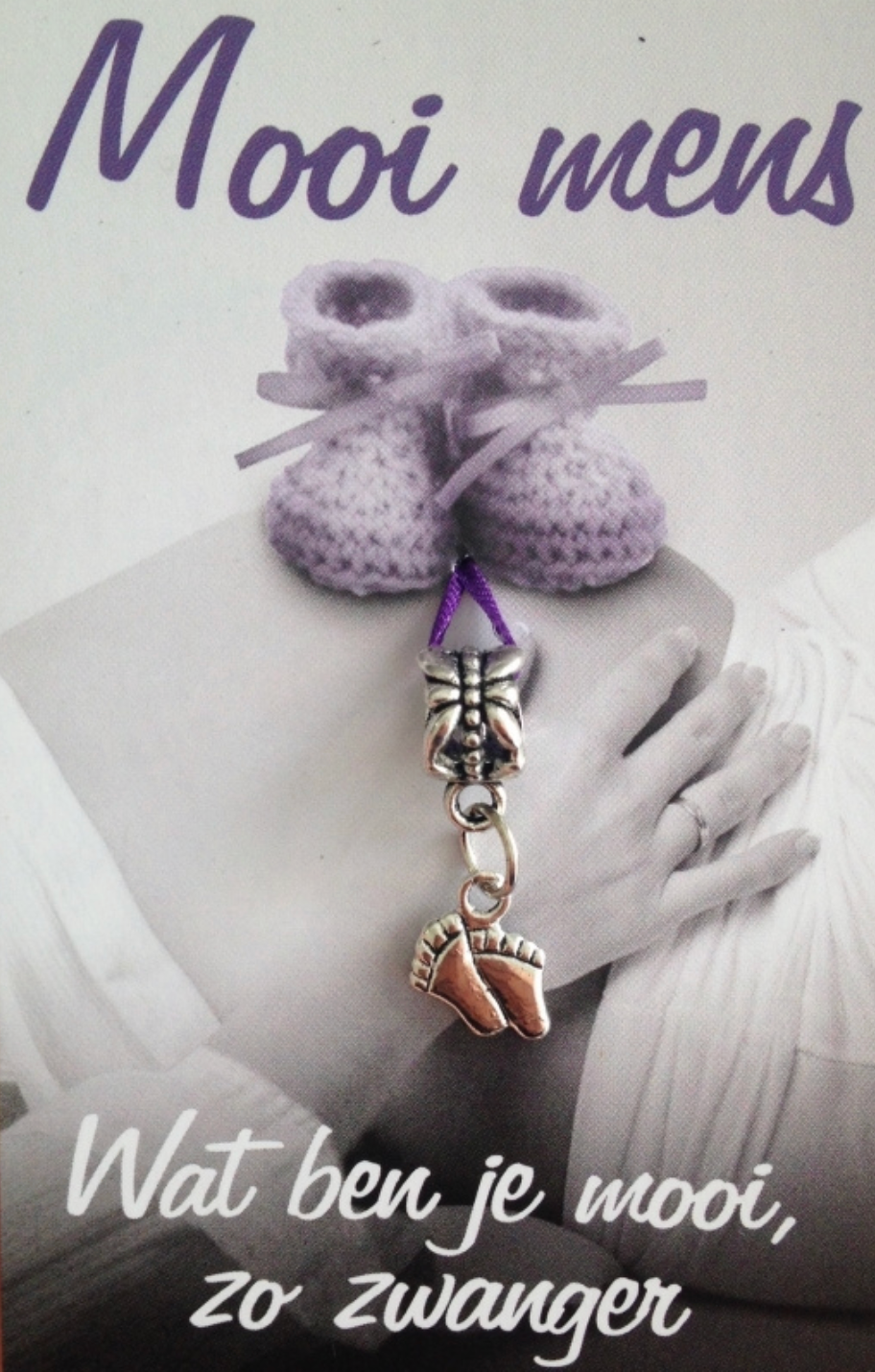 Pregnant person with crochet baby booties and a foot charm. Text: