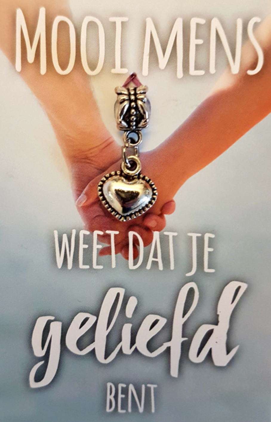 Two hands holding a heart-shaped charm. Text reads: