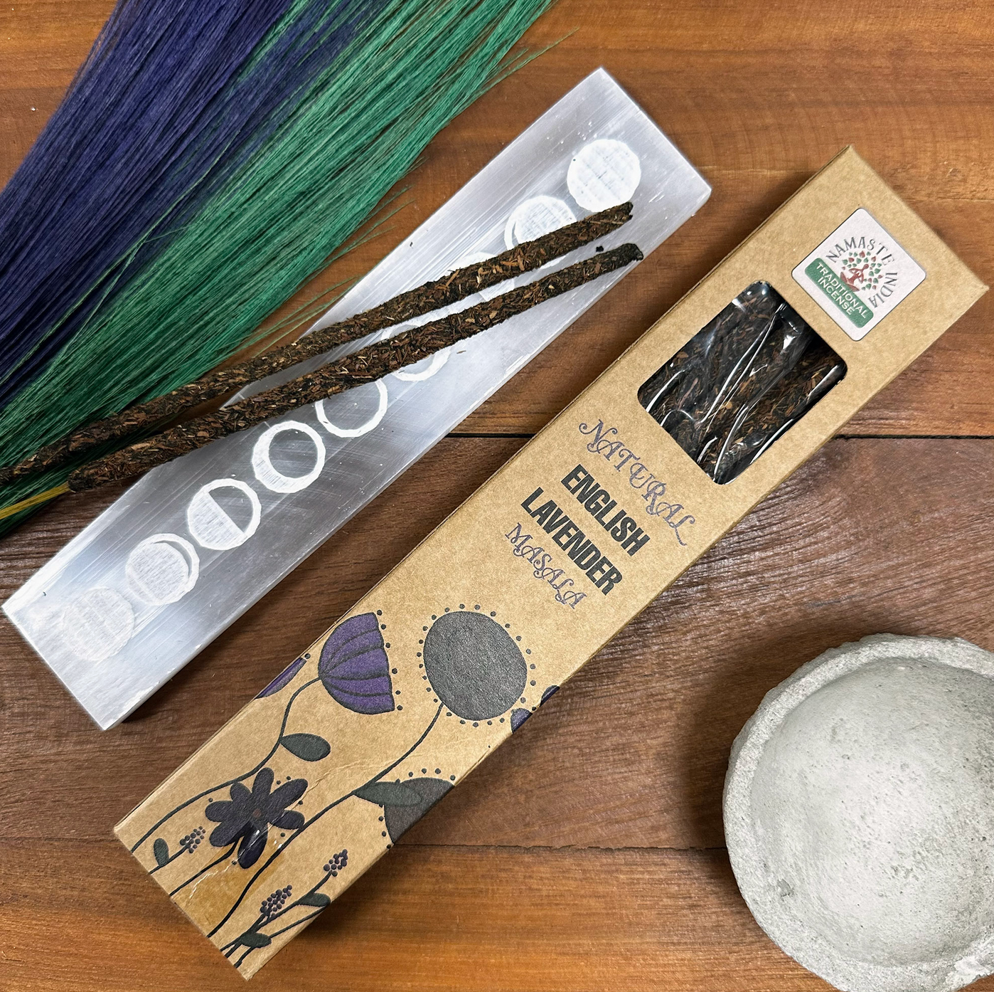 Wierook en wierookhouder met lavendel en groen op een houten ondergrond.