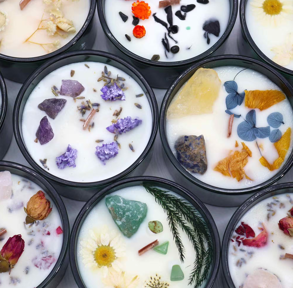 Diverse ronde kaarsen met gedroogde bloemen en kleurrijke botanische versieringen, gerangschikt in een raster