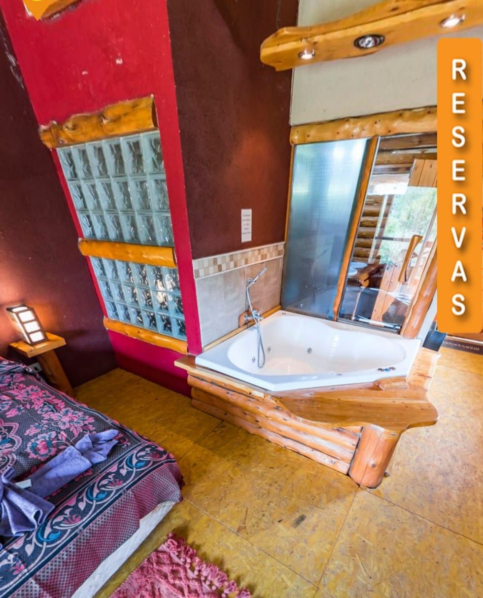 Habitación acogedora con jacuzzi en la esquina, espejo grande y un letrero vertical de “RESERVAS” junto a la puerta.