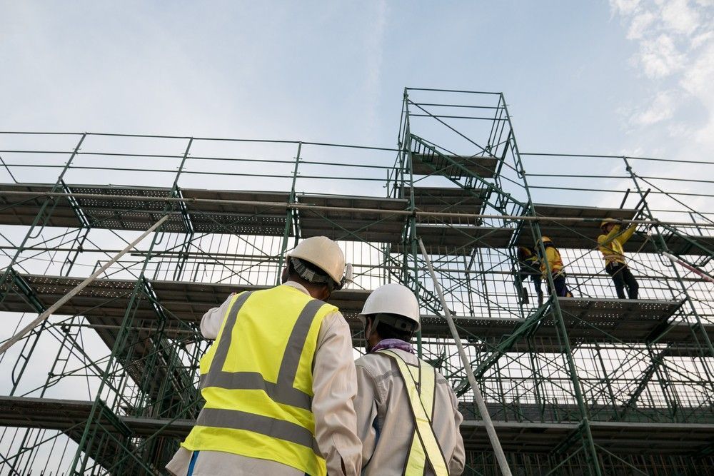 A Couple Of Construction Workers Are Standing Near Scaffolding — Fahlstrom Scaffolding Cairns Pty Ltd in Gordonvale, QLD