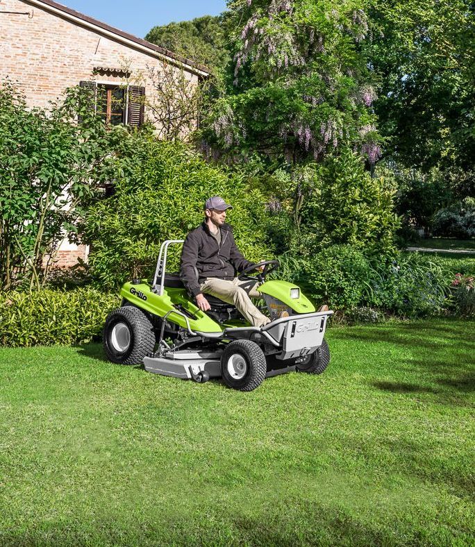 A Person is Mowing a Lush Green Lawn With a Lawn Mower — Stockers & Partridge In Dungog, NSW