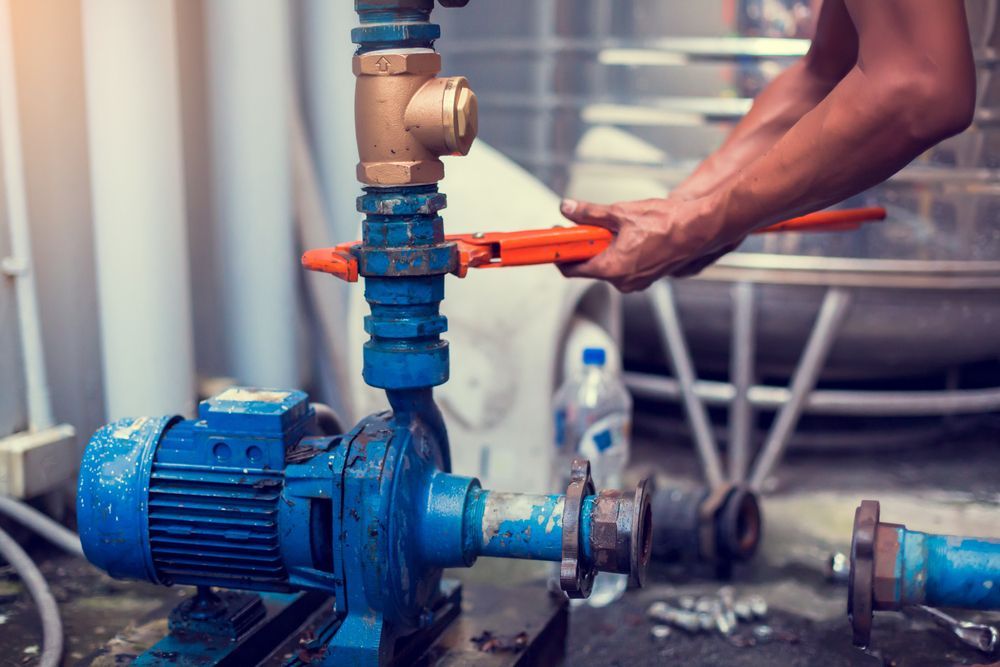 A Man is Fixing a Water Pump With a Wrench — Stockers & Partridge In Paterson, NSW