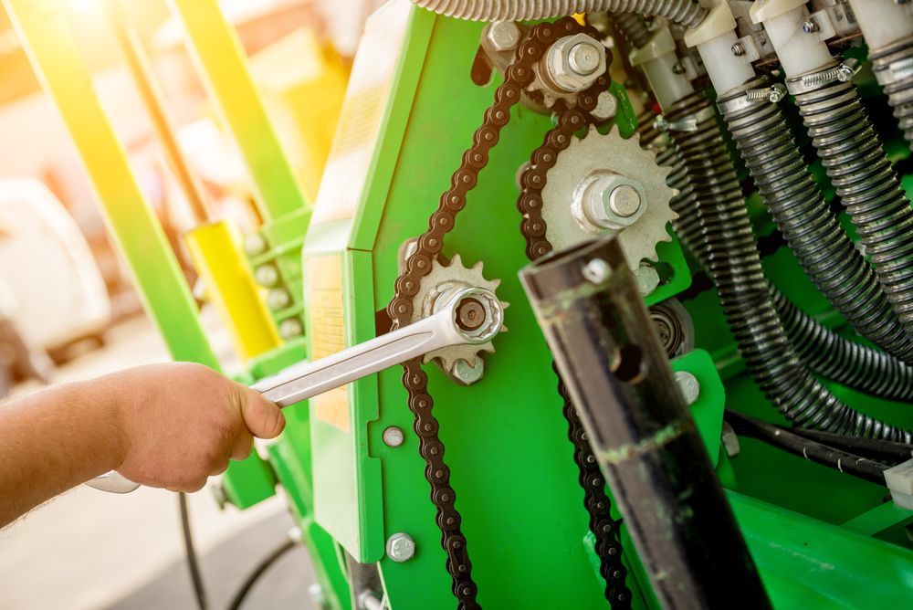 A Man is Working on a Green Machine With a Wrench — Stockers & Partridge In Paterson, NSW
