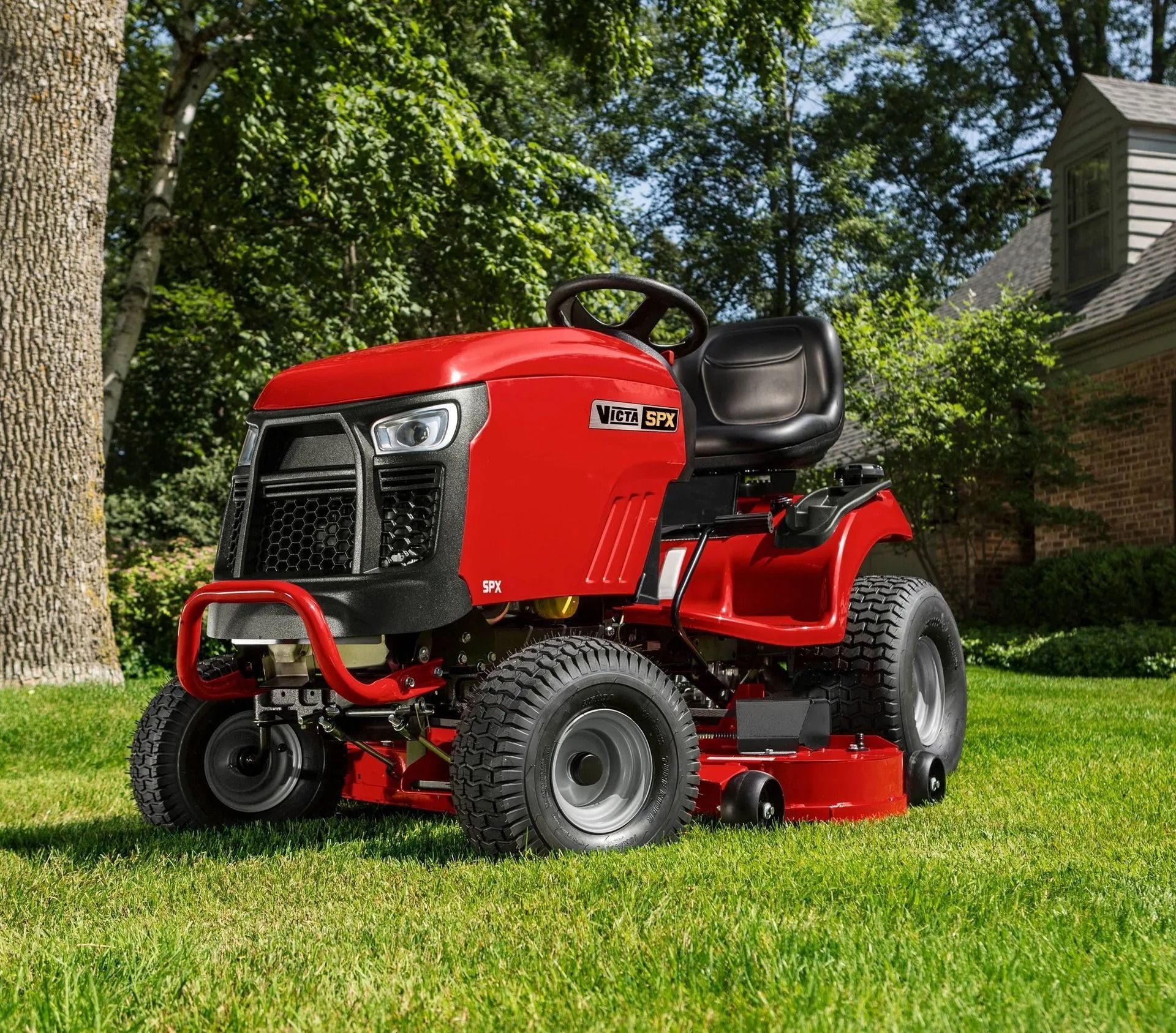 Red riding lawn mower on green grass in a yard — Stockers & Partridge In Raymond Terrace, NSW