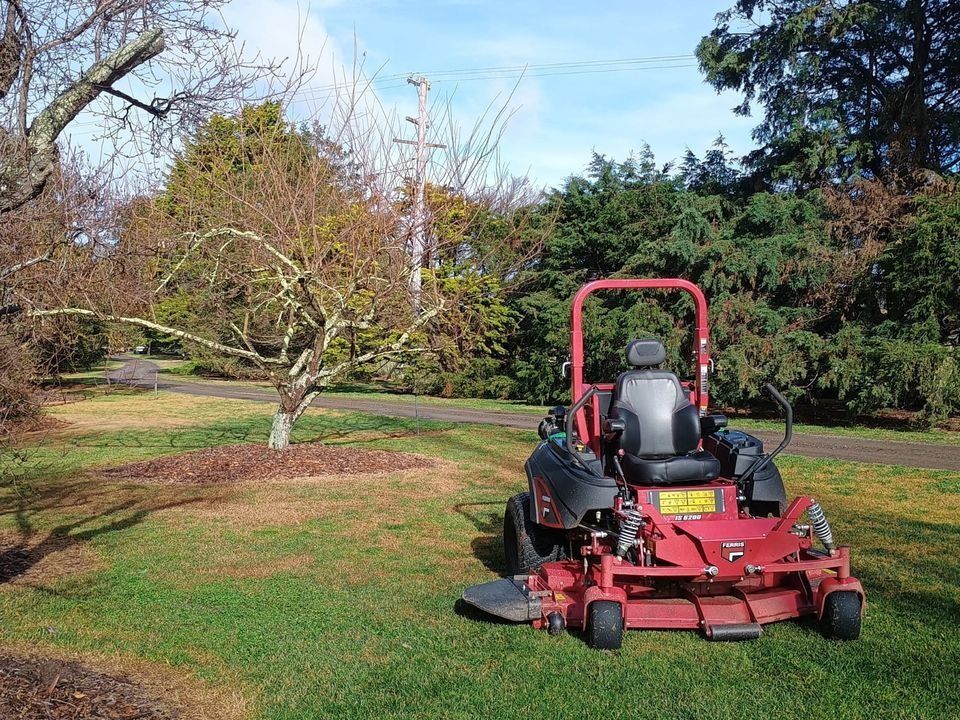A Red Lawn Mower is Parked in a Lush Green Field — Stockers & Partridge In Paterson, NSW