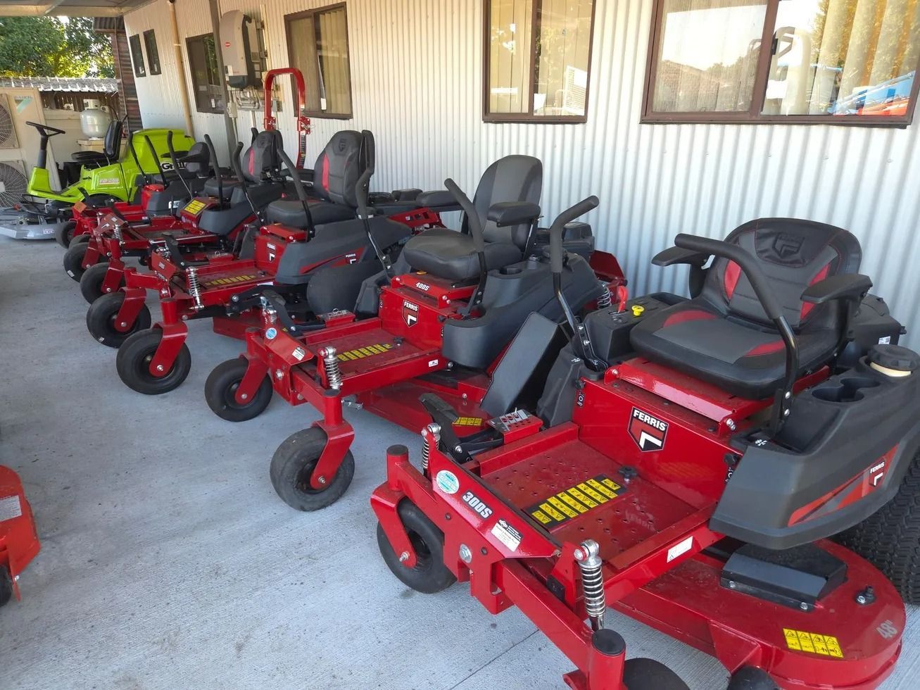 A Man is Riding a Red Lawn Mower on a Lush Green Lawn — Stockers & Partridge In Paterson, NSW