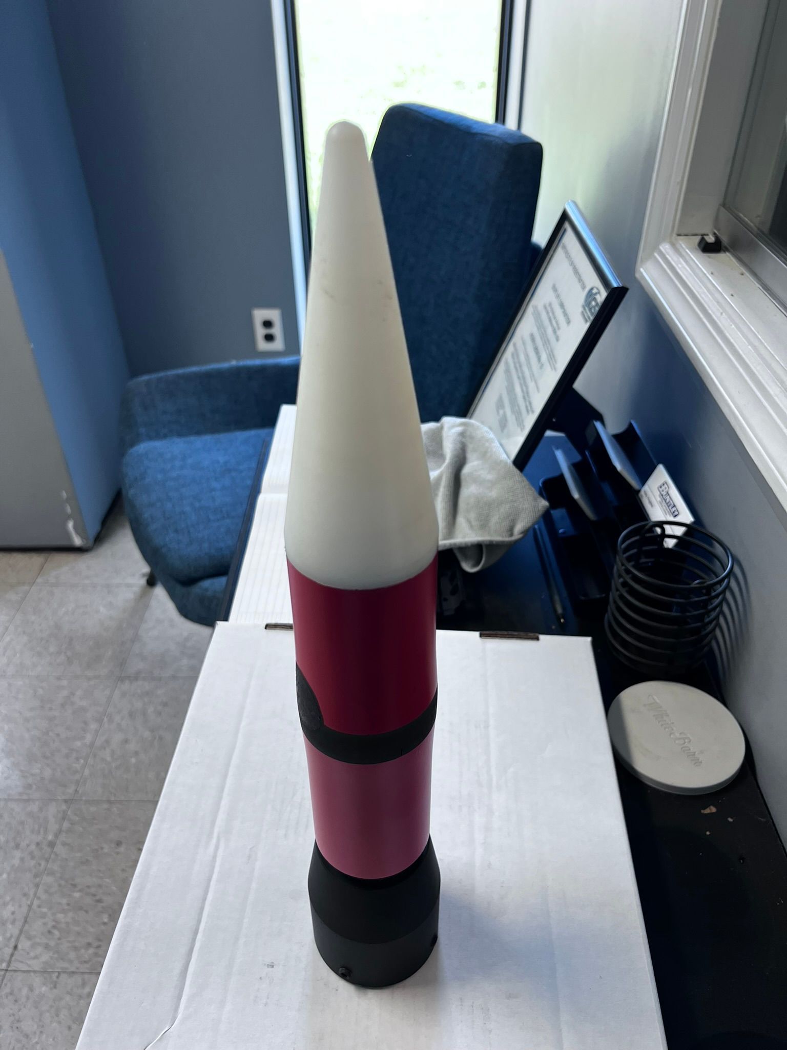 A red and white rocket is sitting on a desk in front of a computer.