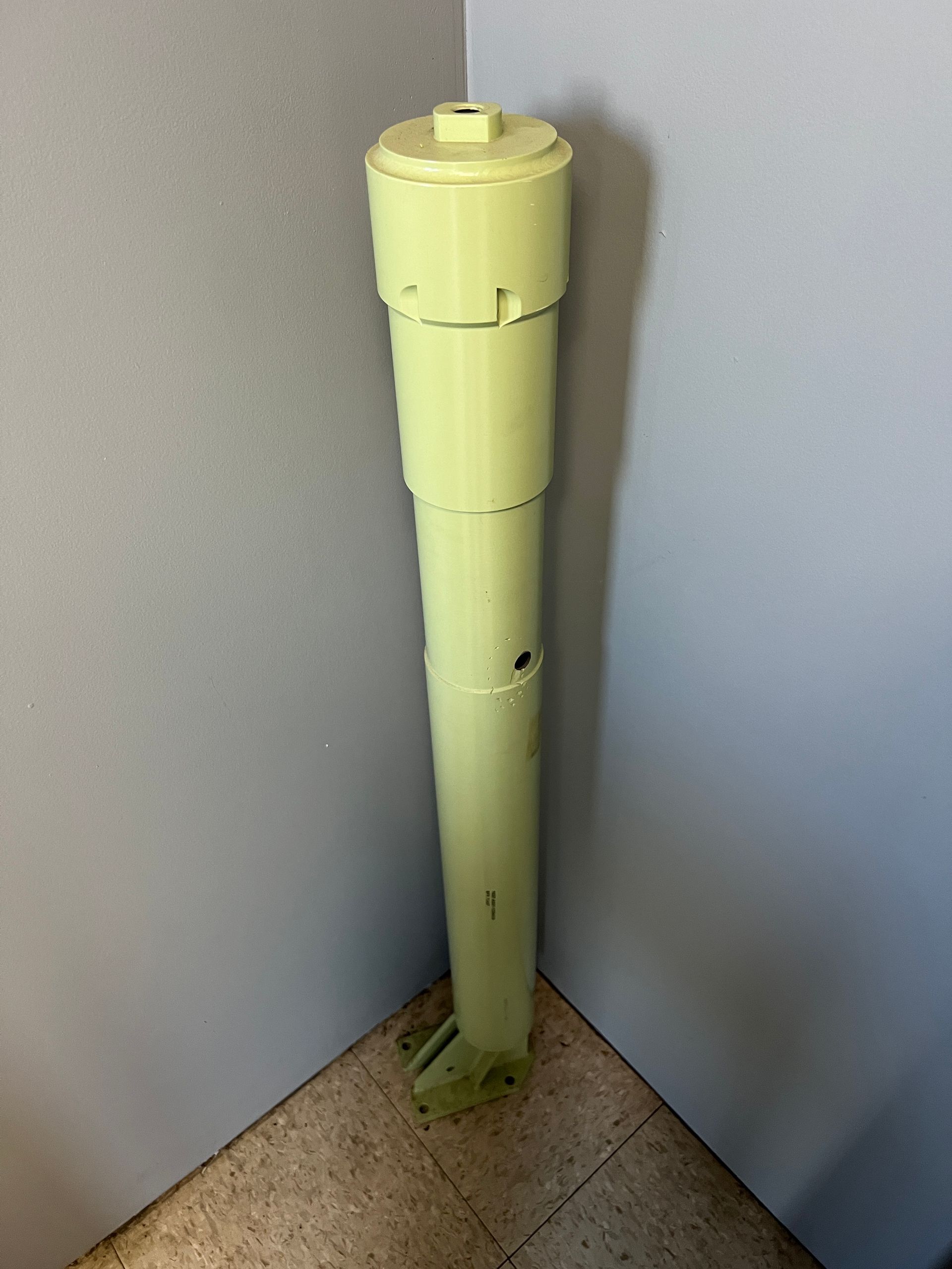 A yellow pipe is sitting in the corner of a room