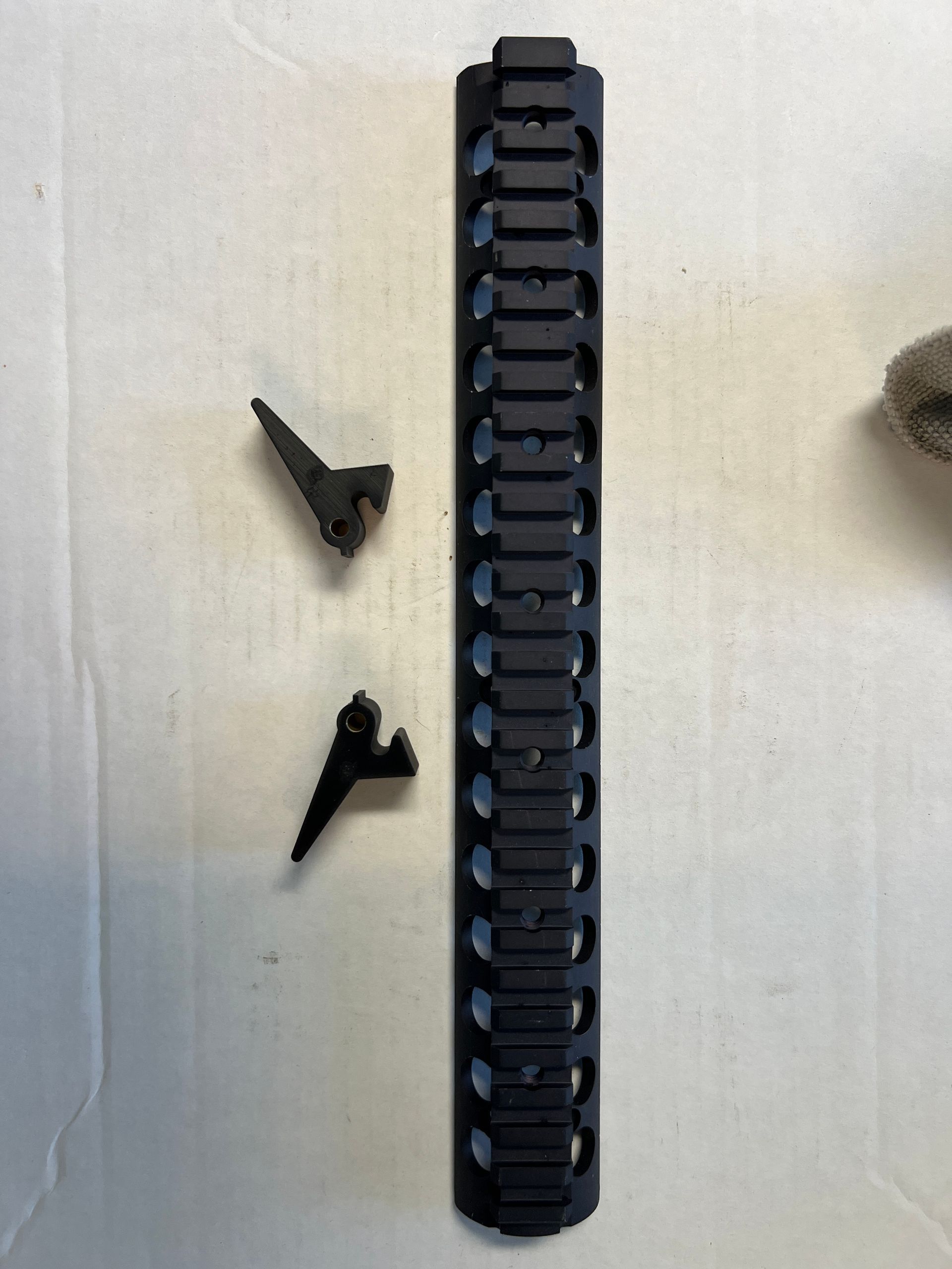 A black rail with two pieces of metal on it is sitting on a white surface.