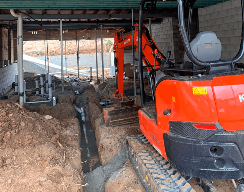 Mini excavator digging trench for underground conduit in Phoenix