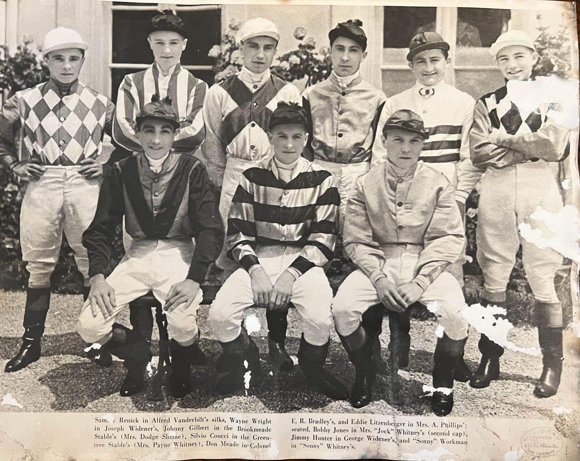Vintage team portrait of eight polo players in striped uniforms and helmets, posing with mallets on horseback and on foot.
