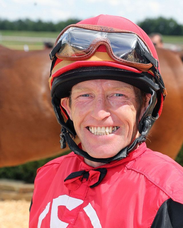 James Graham earing a red helmet smiling at the camera before the race.
