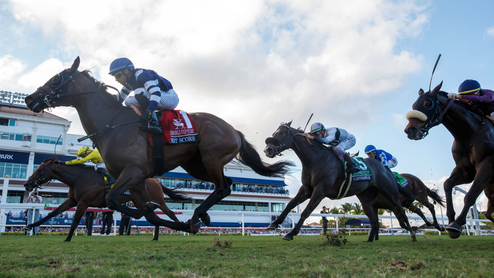 Horse race with jockeys on dark horses sprinting past grandstands under a cloudy sky