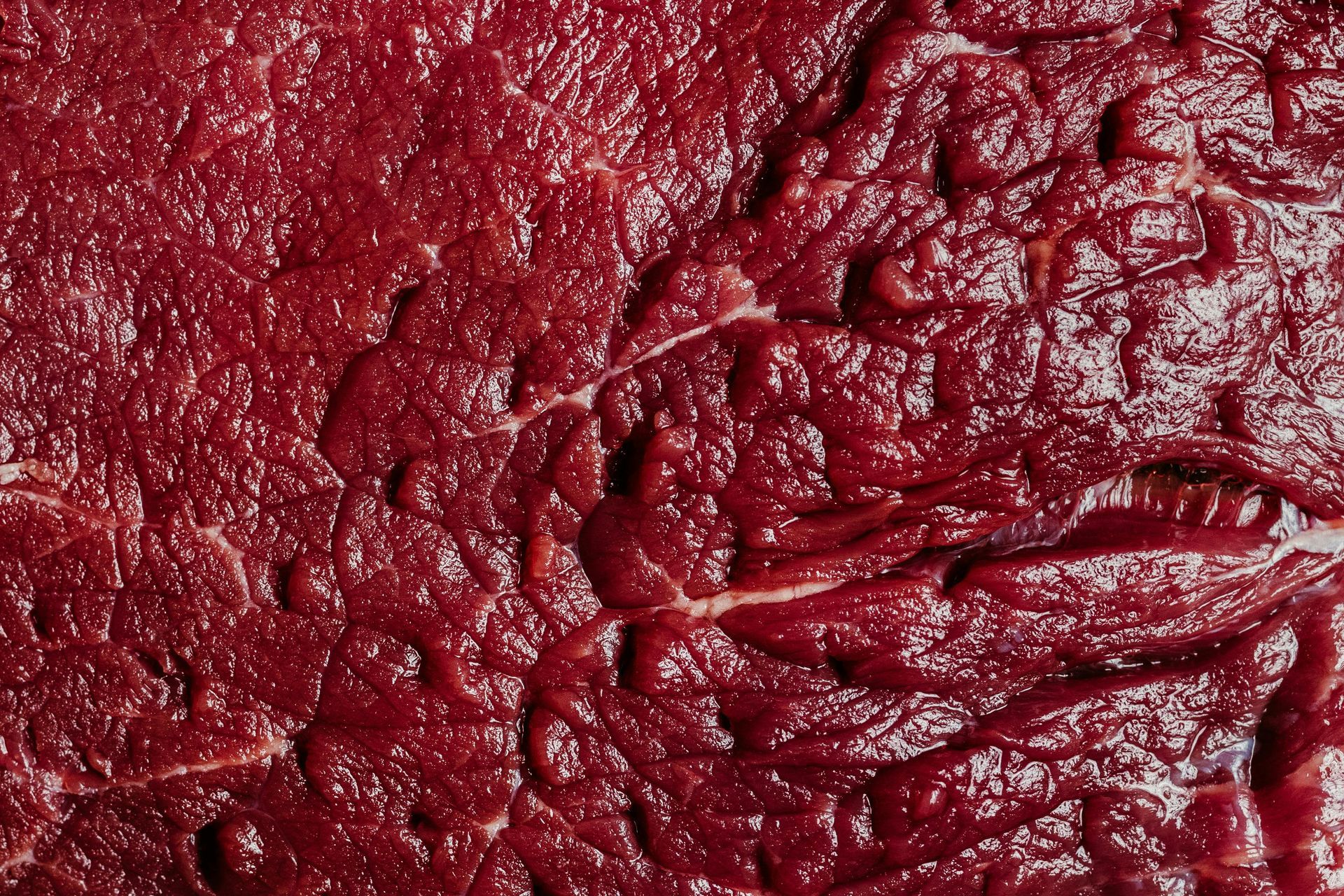 Close-up of wrinkled dark red textured surface with glossy highlights