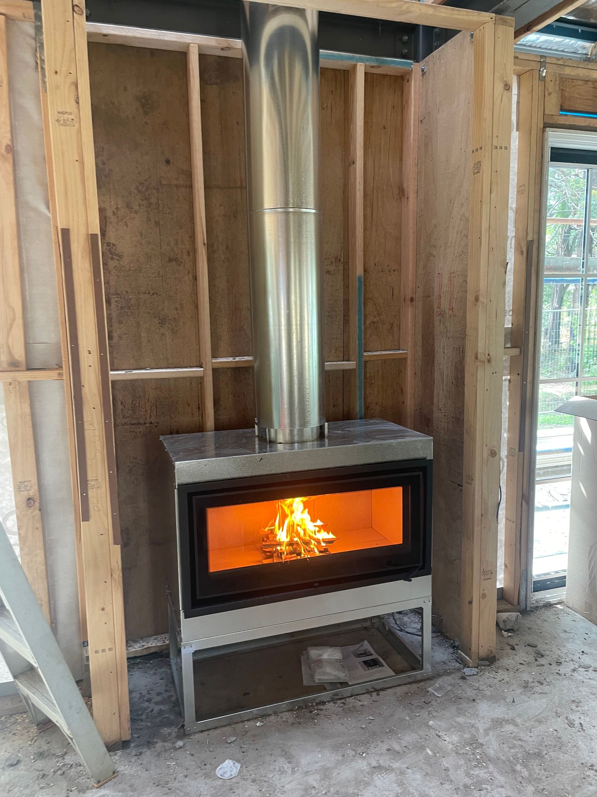 Wood-burning fireplace in a wooden frame. Stainless steel chimney and fire burning inside.