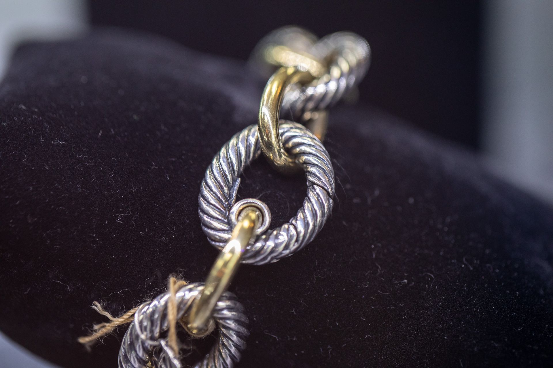 Close-up of a silver rope chain with gold links on black fabric