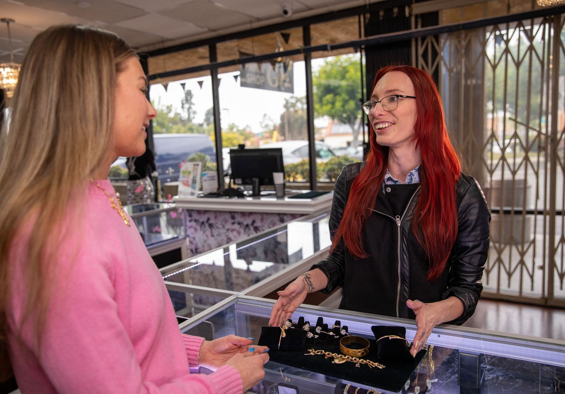Woman showing jewelry to another woman at a jewelry store counter.
