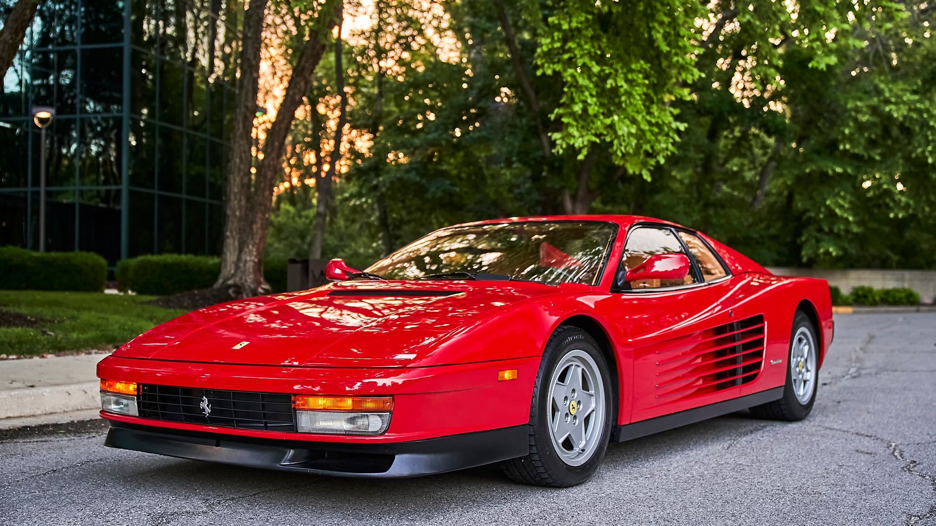 A red ferrari testarossa is parked in front of a building.