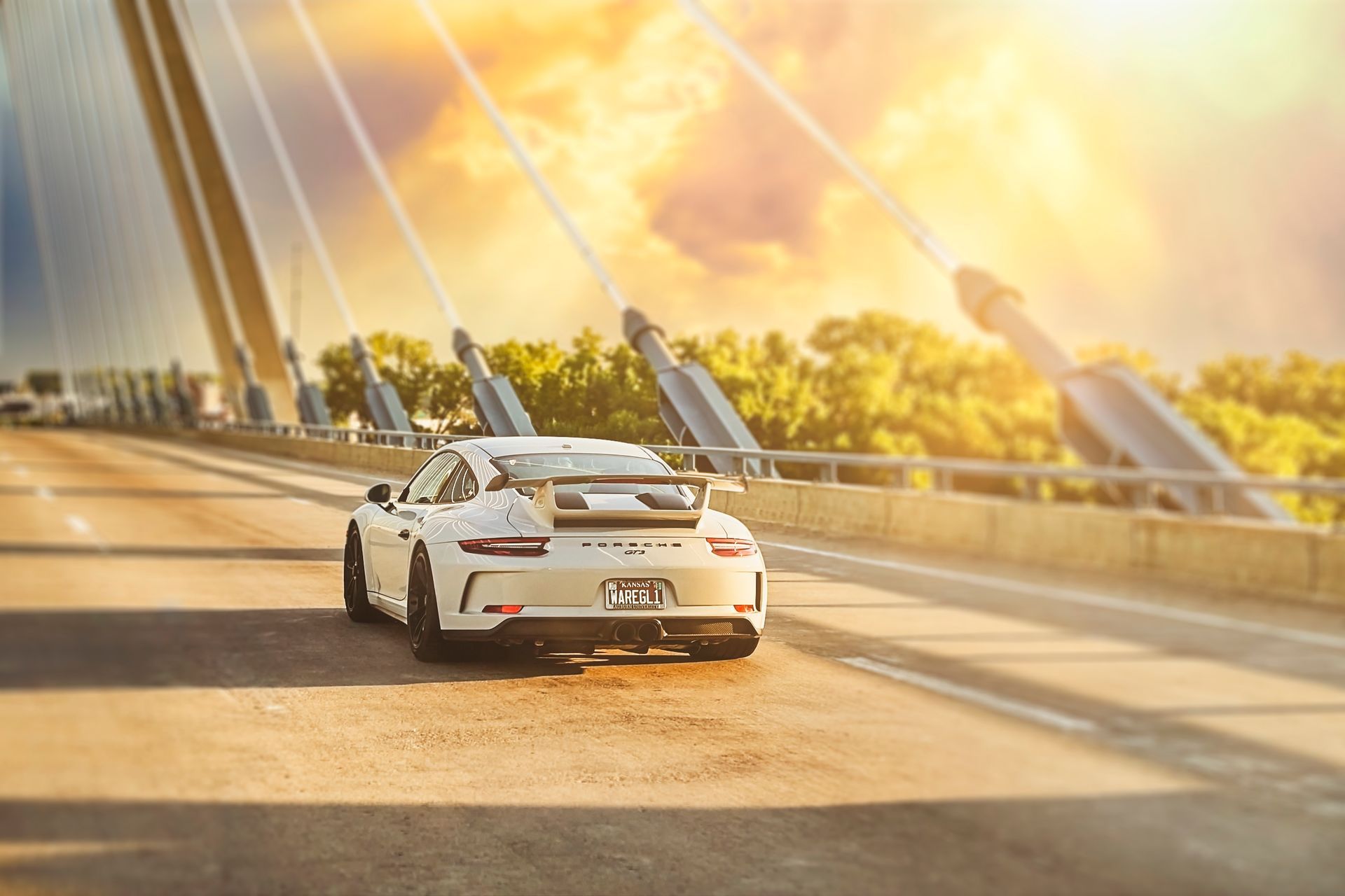 A white porsche 911 gt3 rs is driving on a bridge.