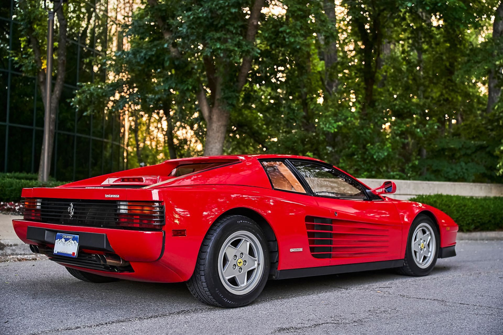 A red ferrari testarossa is parked on the side of the road.