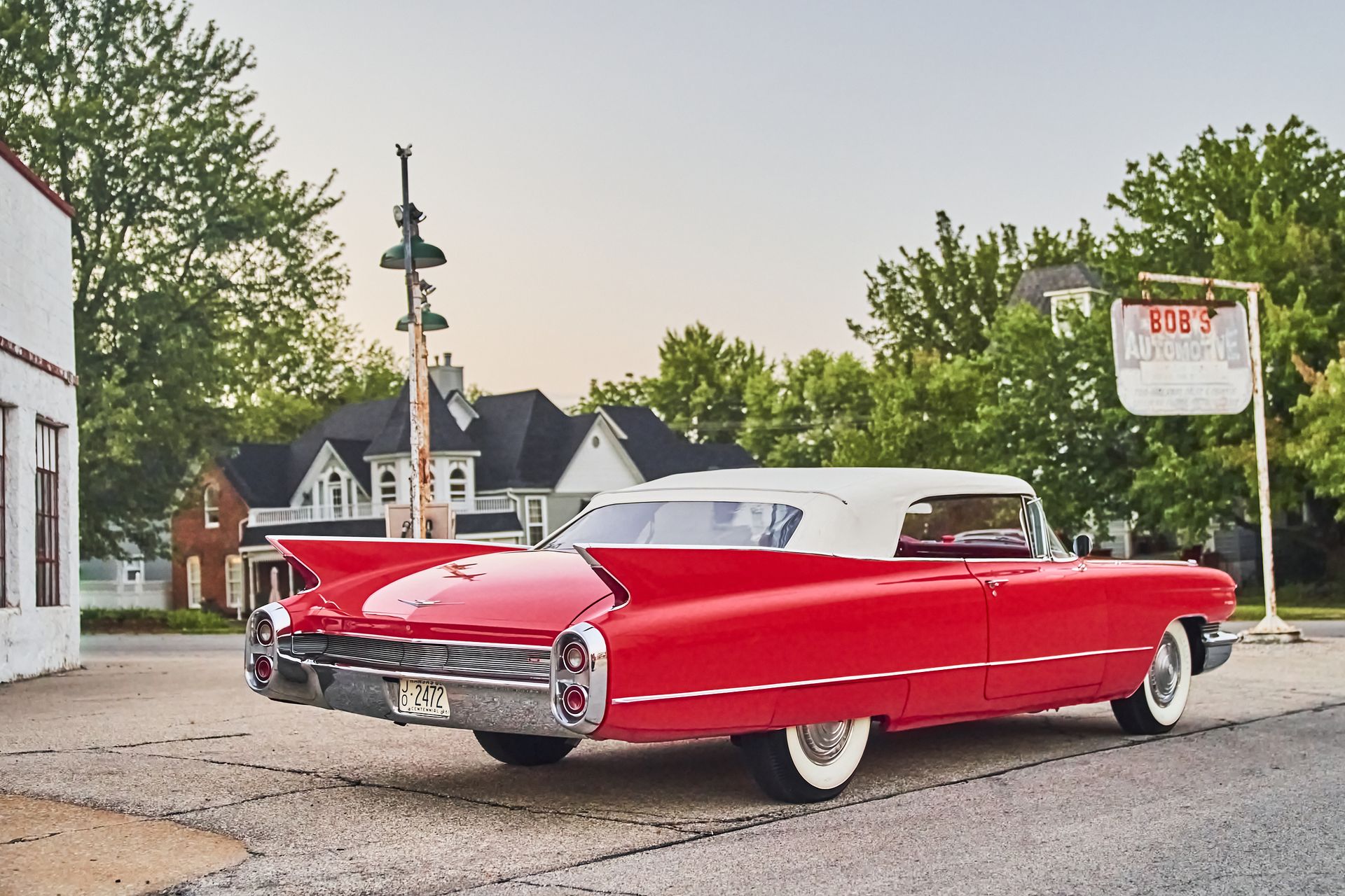 A red cadillac is parked in front of a gas station