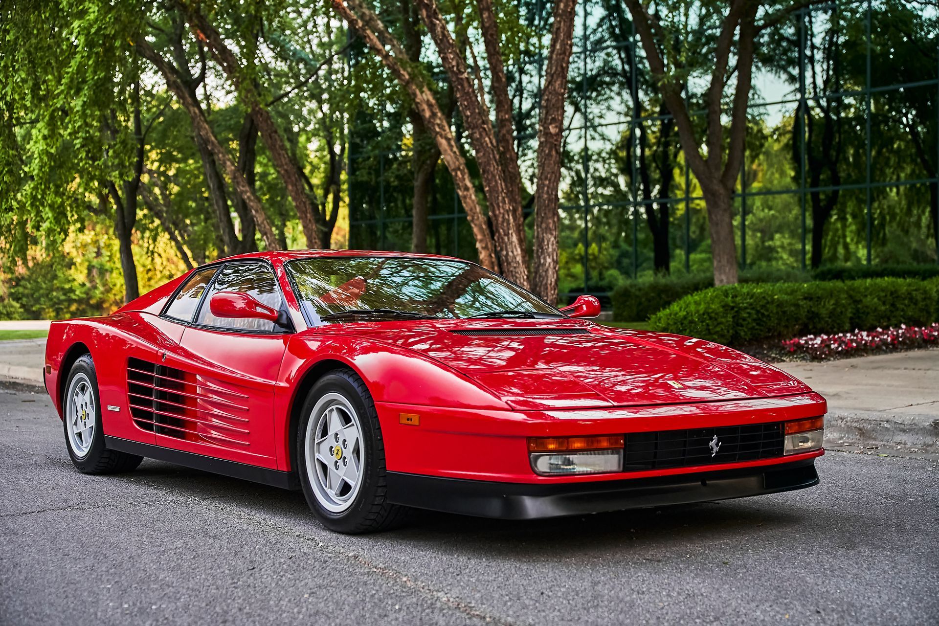 A red ferrari testarossa is parked on the side of the road.