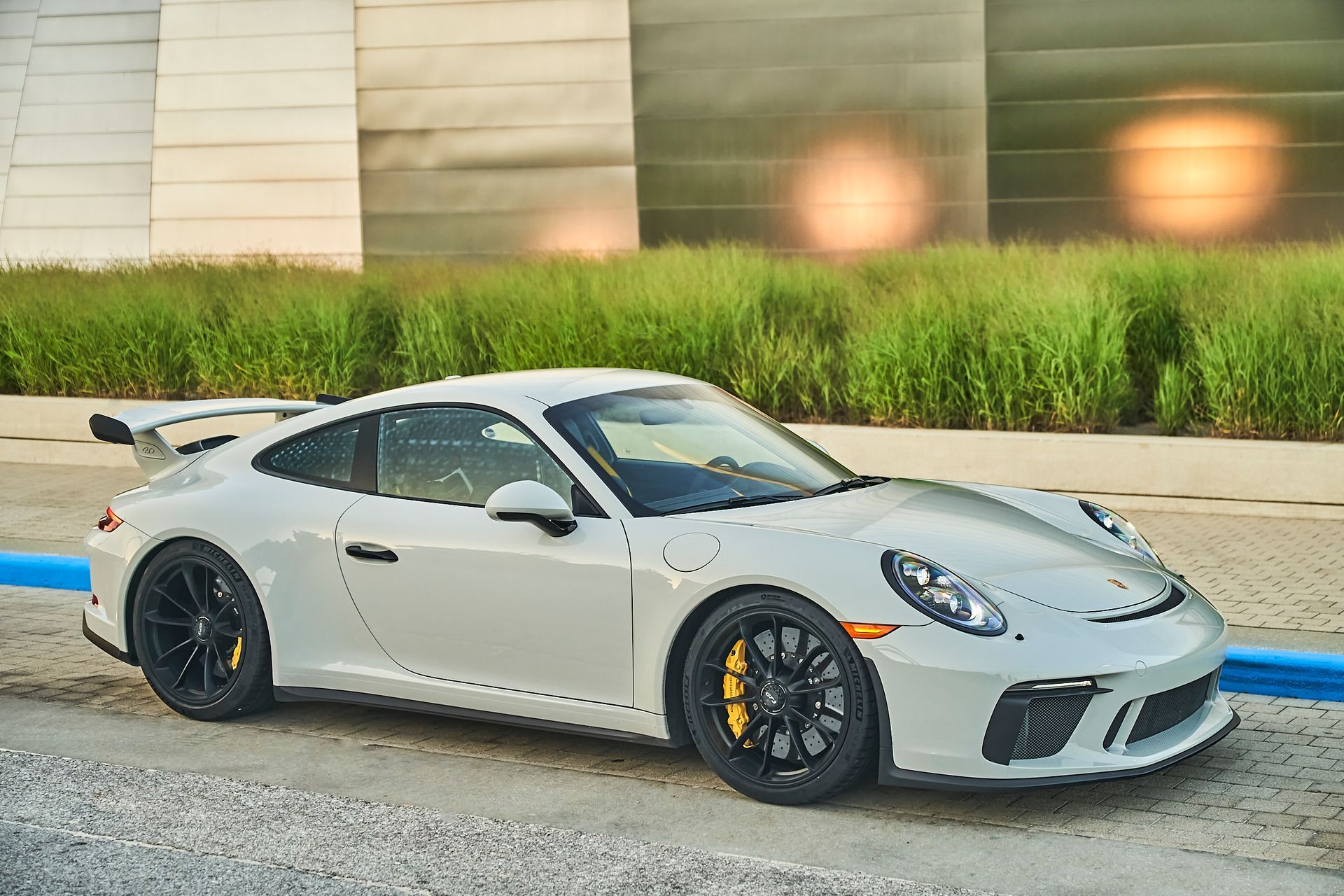 A white porsche 911 gt3 is parked in a parking lot.