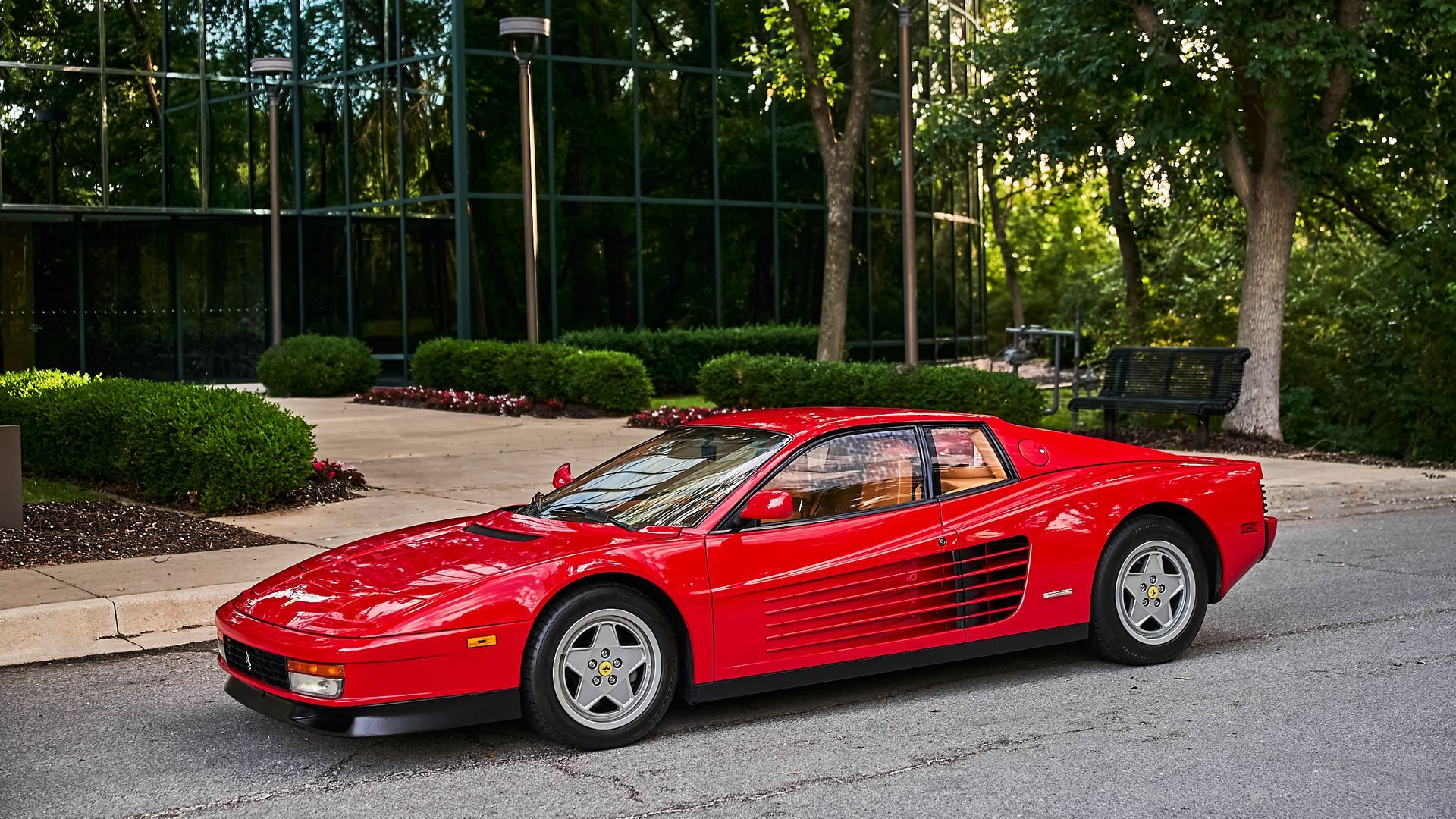 A red ferrari testarossa is parked in front of a building.