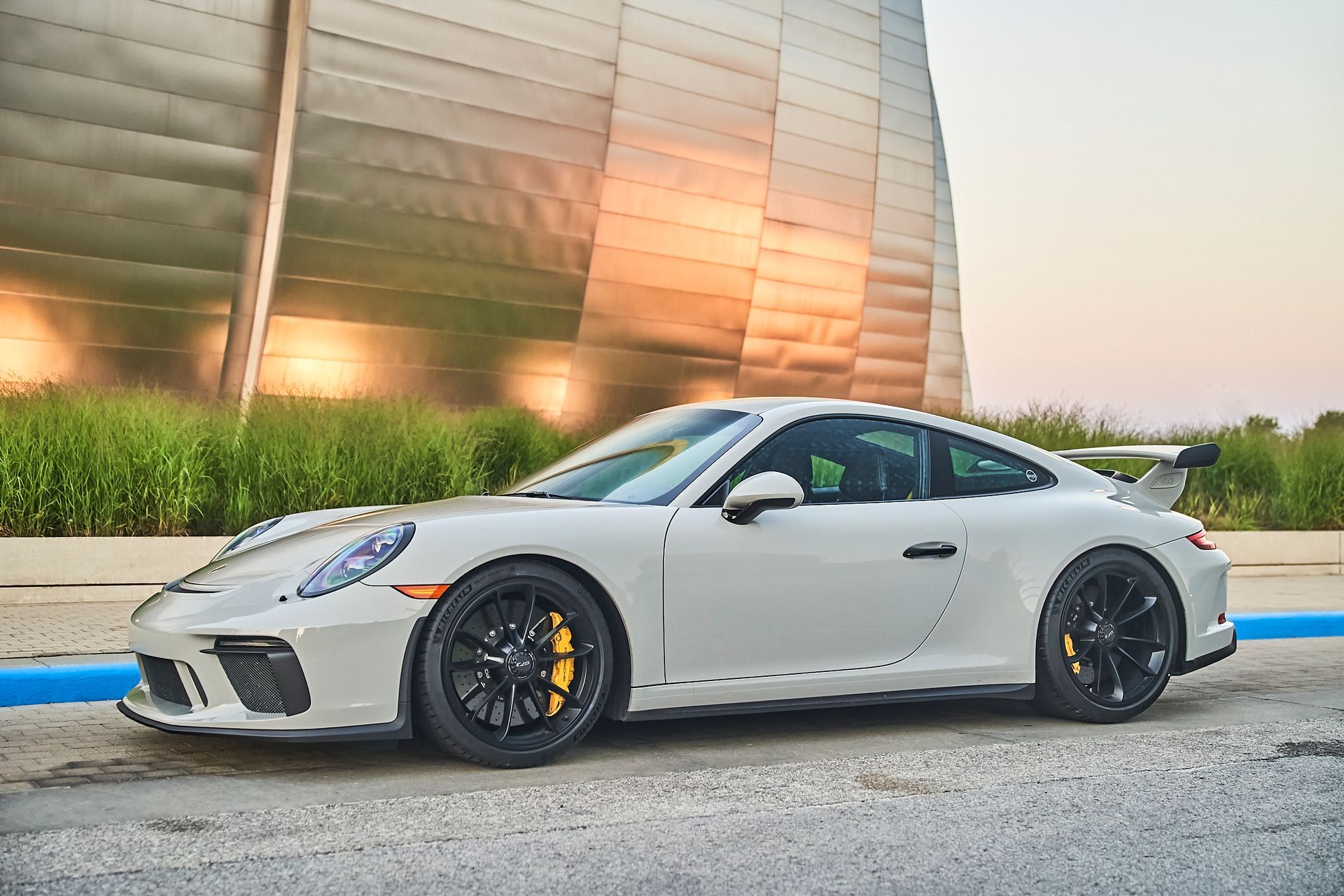 A white porsche 911 gt3 is parked in front of a building.