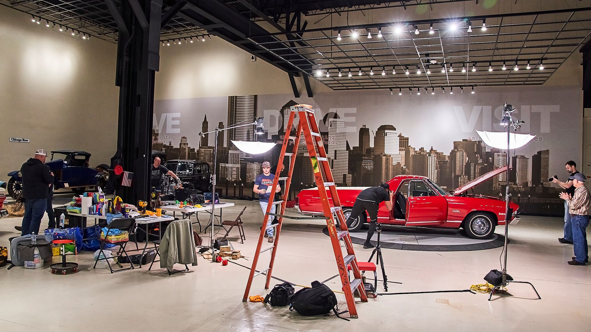 A red mustang is being photographed in a large room