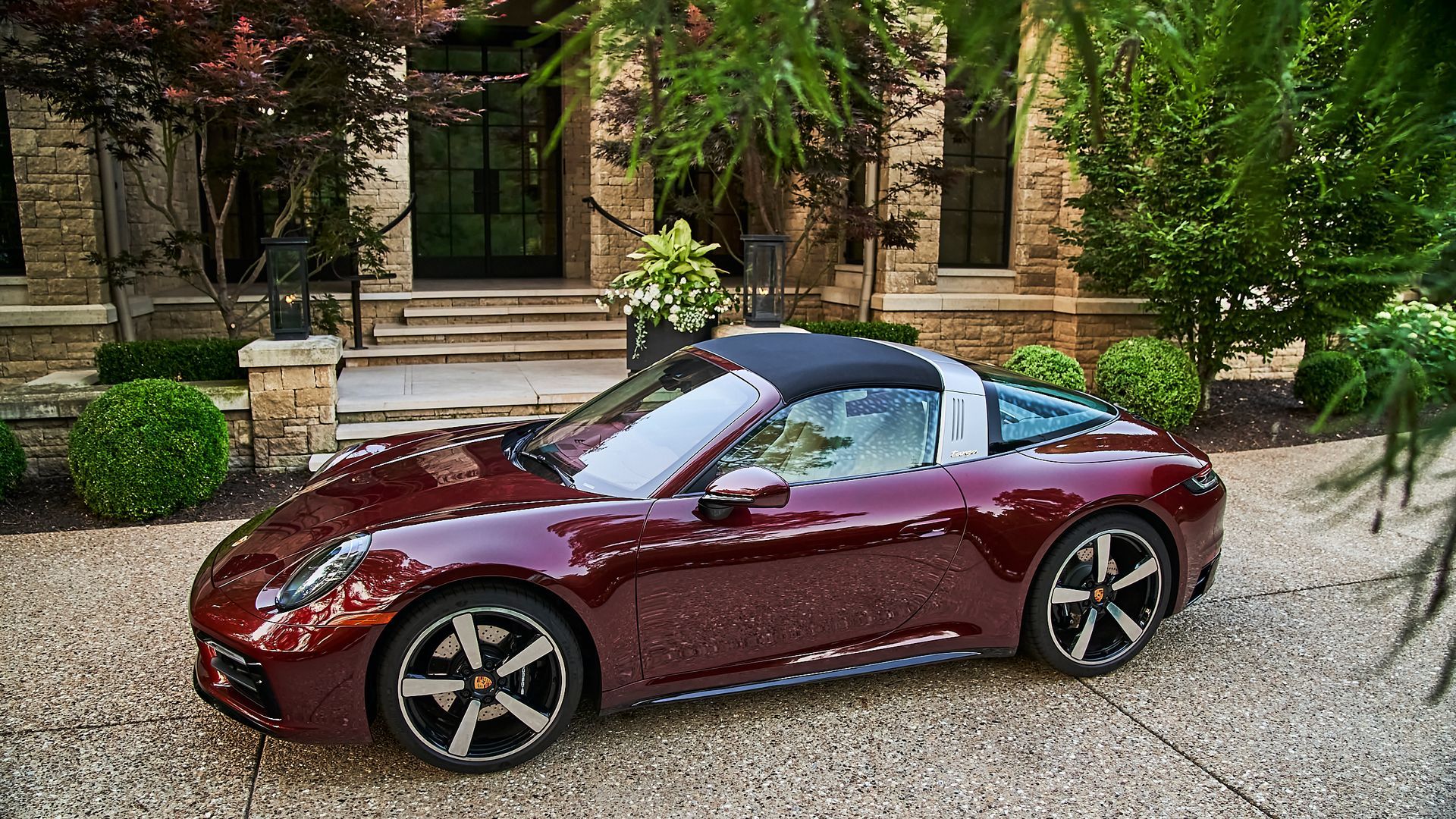 A red porsche targa is parked in front of a house.