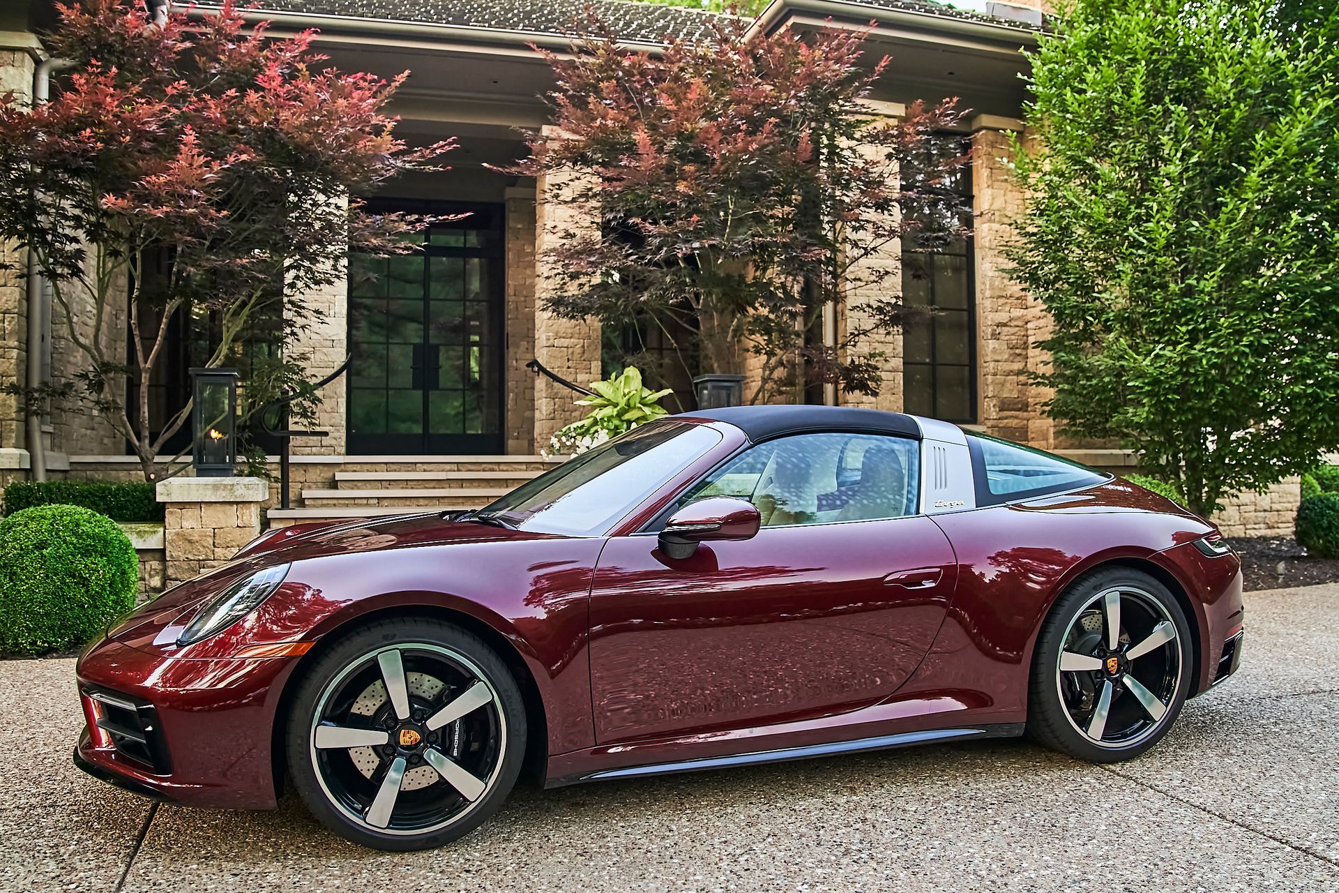 A red porsche targa is parked in front of a house.