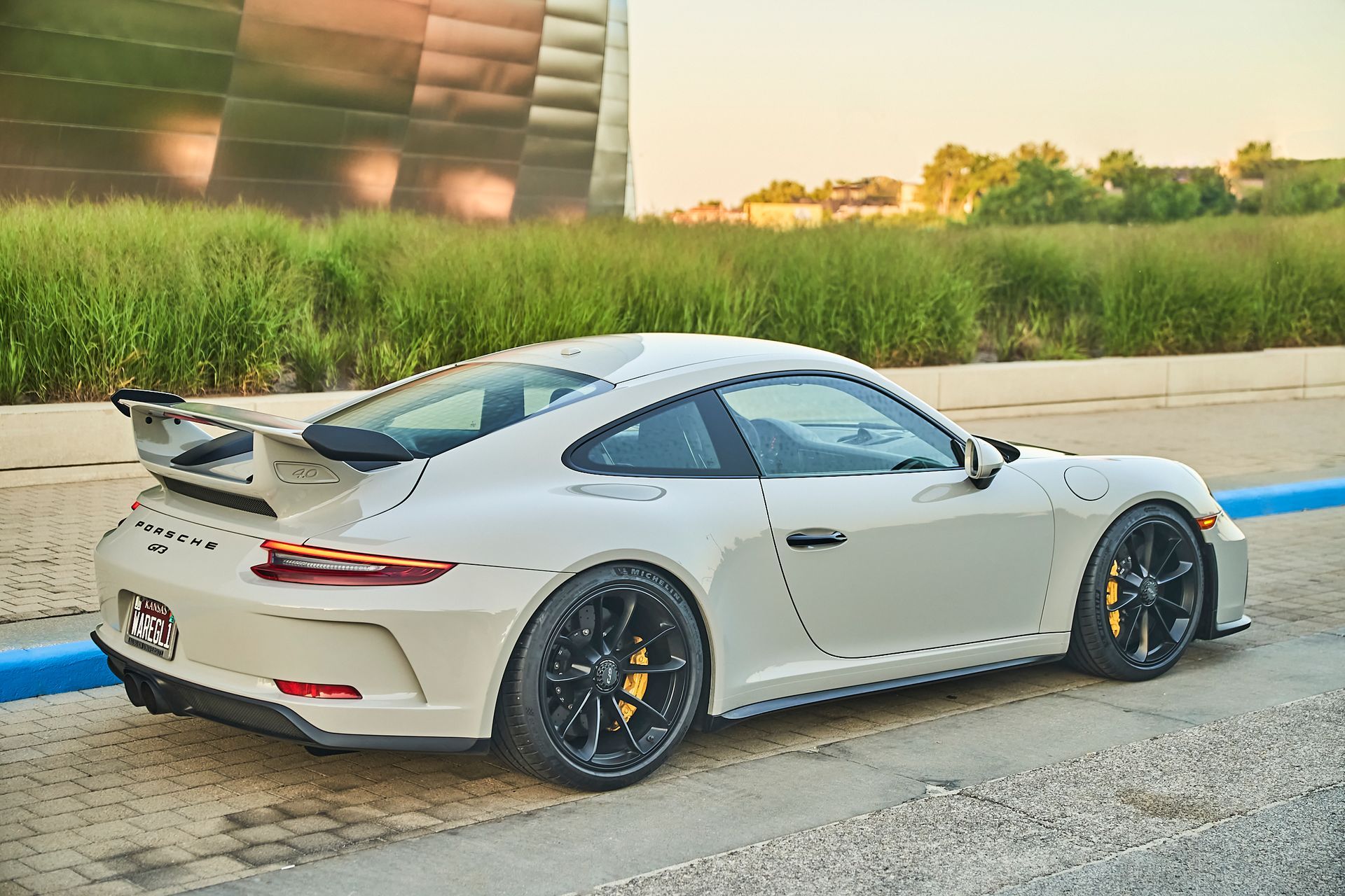 A white porsche 911 gt3 is parked in a parking lot.