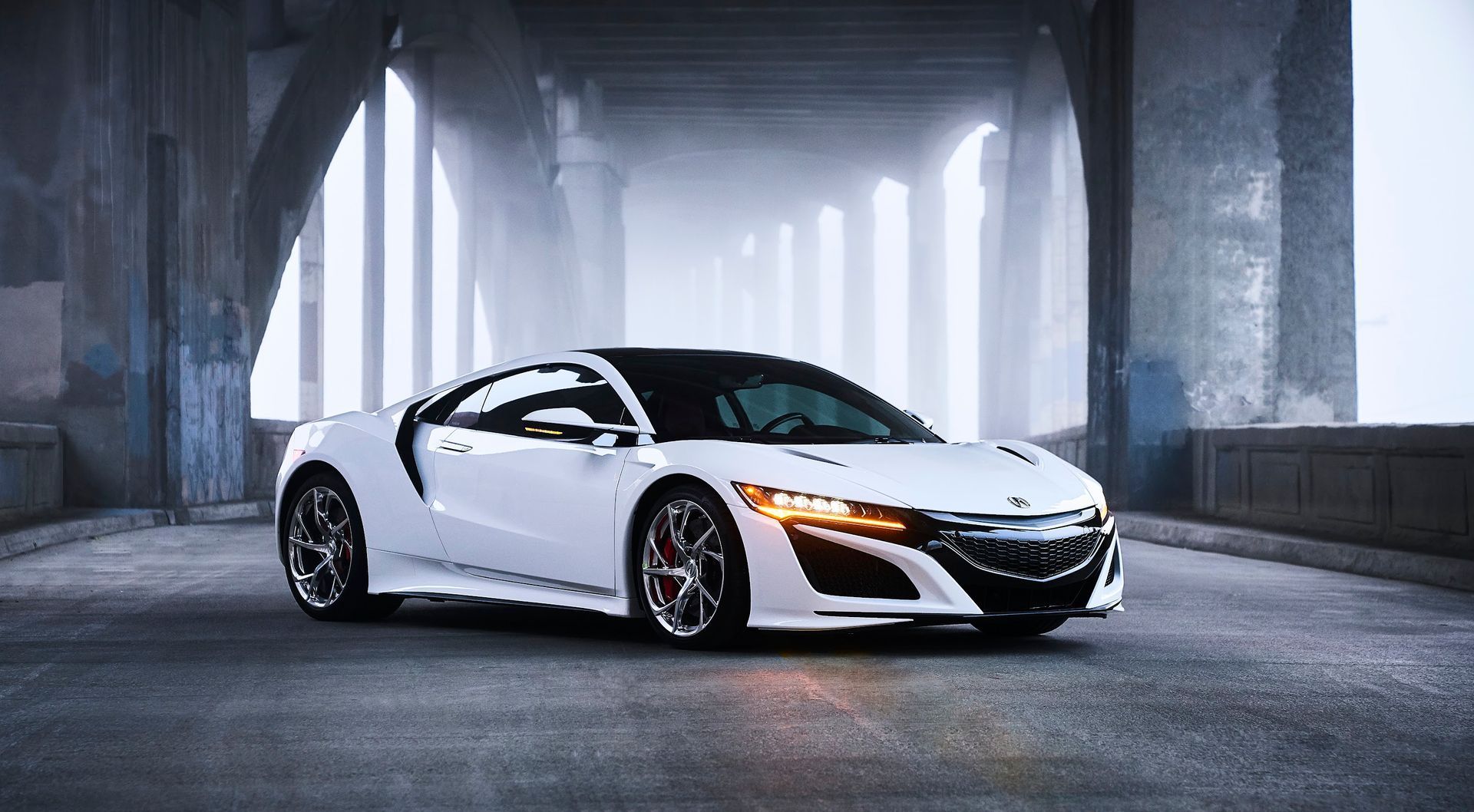 A white sports car is parked under a bridge.