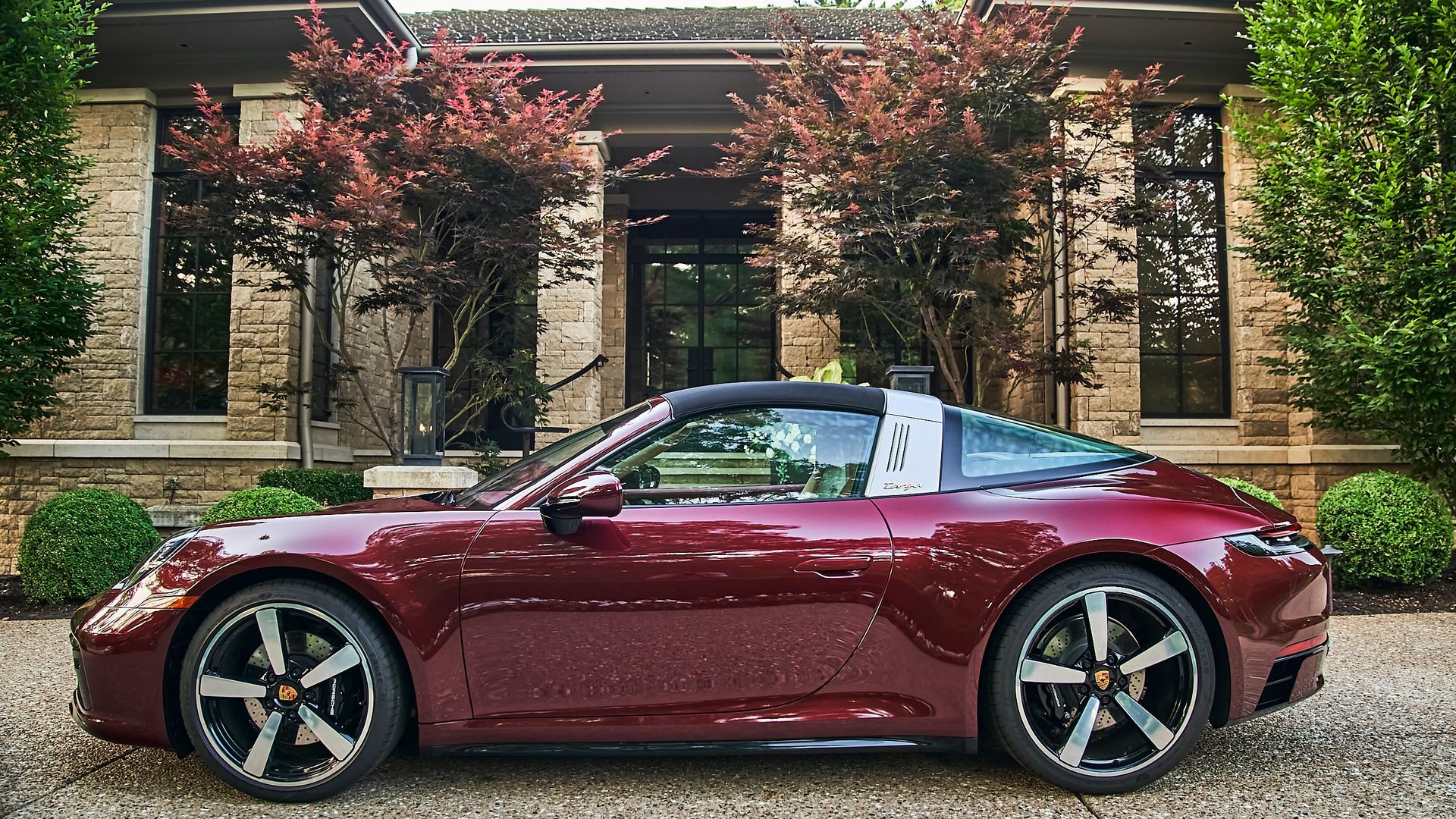 A red porsche targa is parked in front of a house.