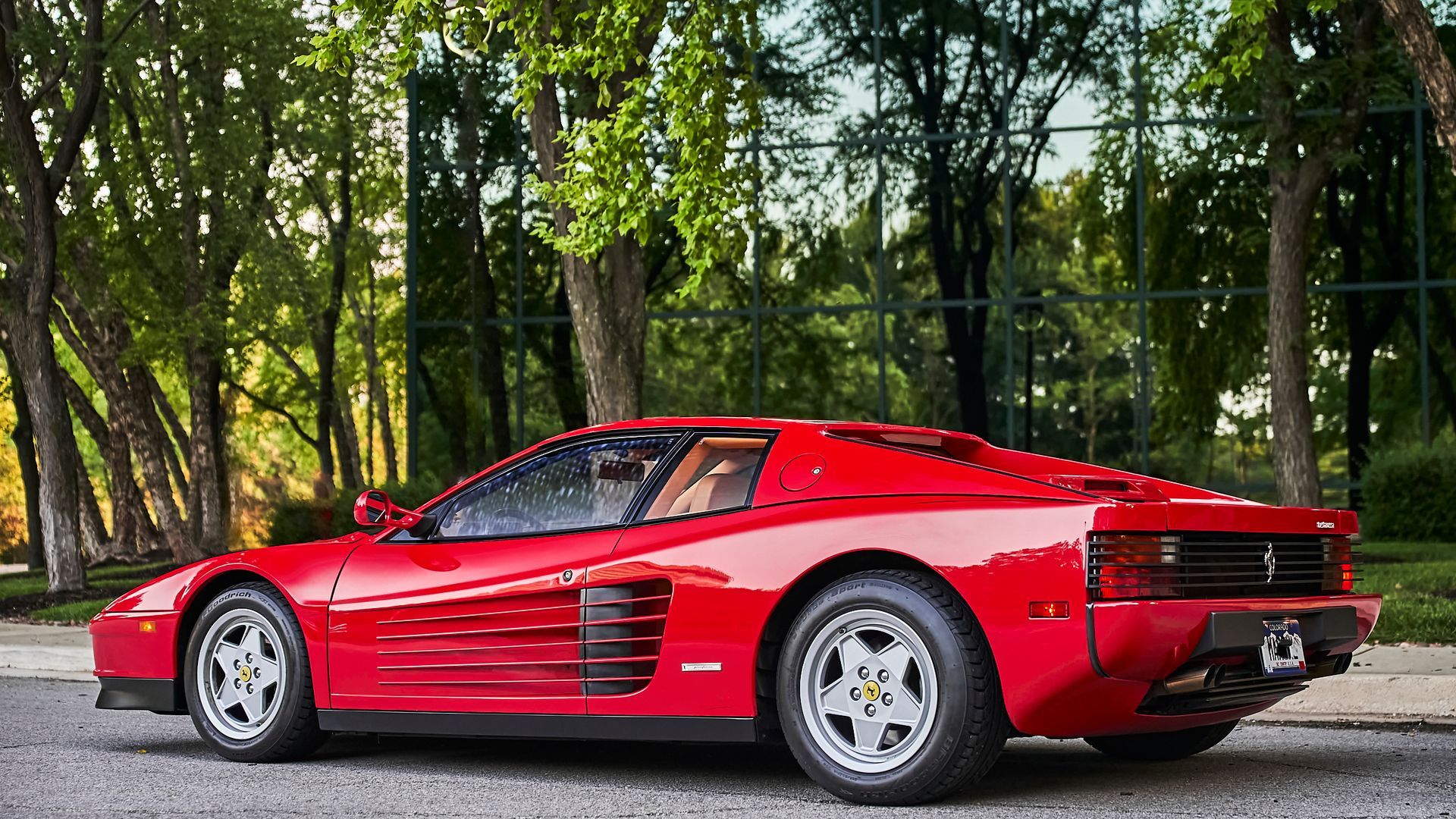 A red ferrari testarossa is parked on the side of the road.