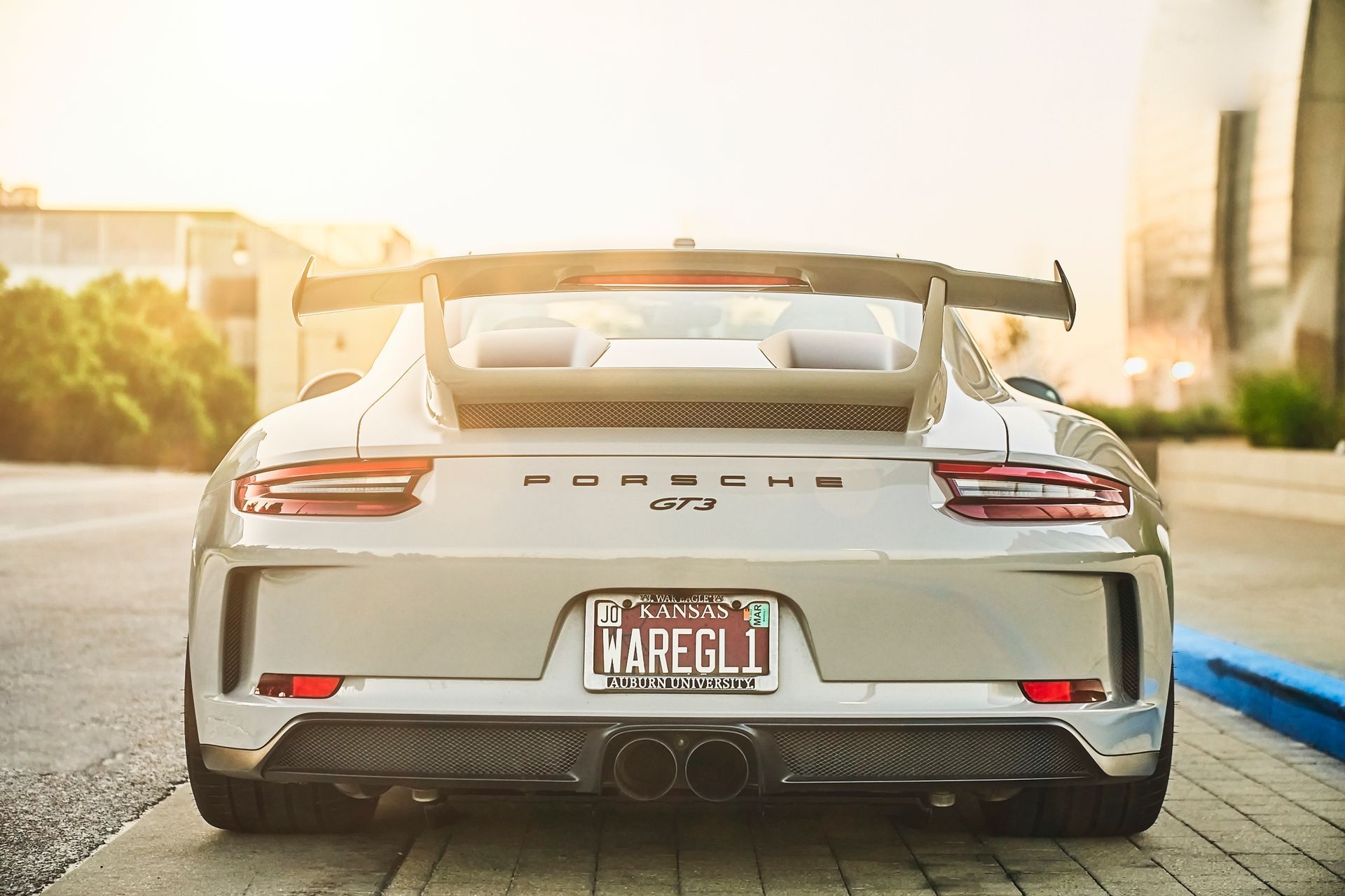 A silver porsche 911 gt3 is parked on the side of the road.
