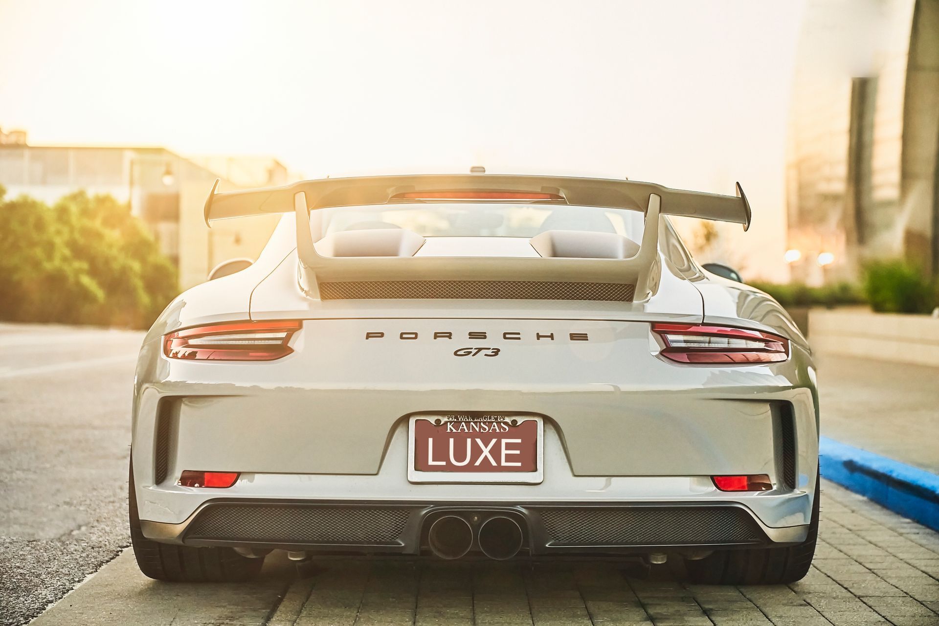 A silver porsche 911 gt3 rs is parked on the side of the road.