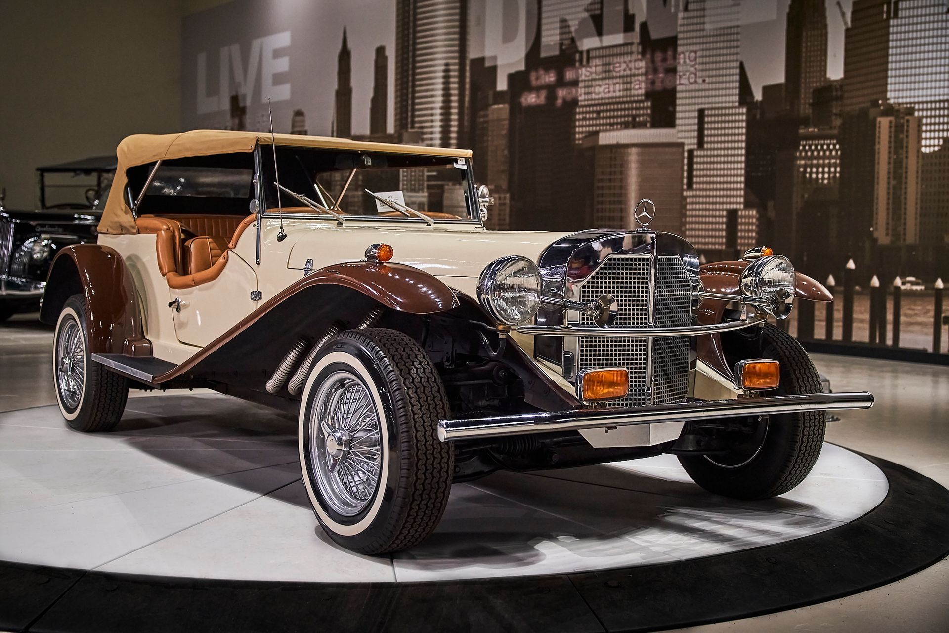 A vintage car is on display in front of a city skyline.