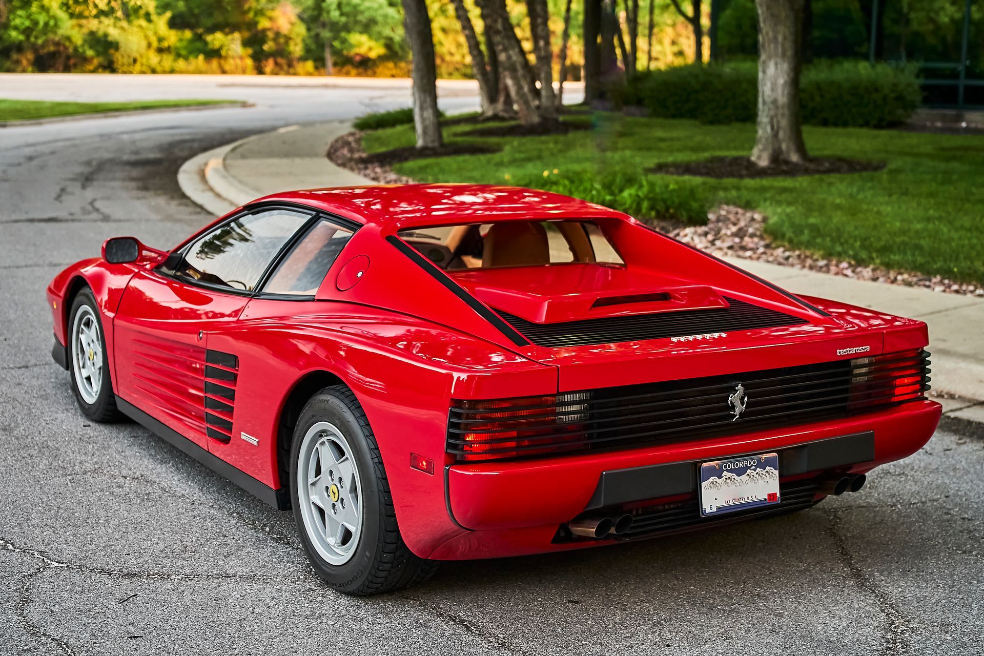 A red ferrari testarossa is parked on the side of the road.