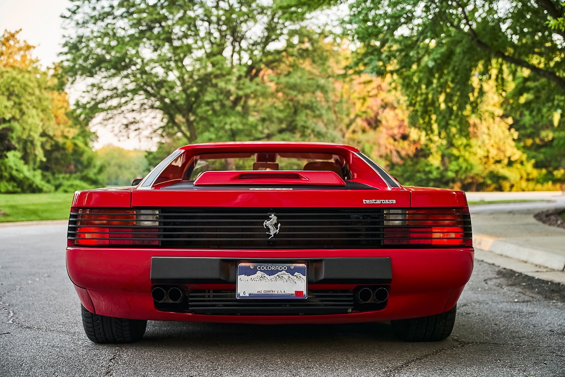 A red ferrari testarossa is parked on the side of the road.