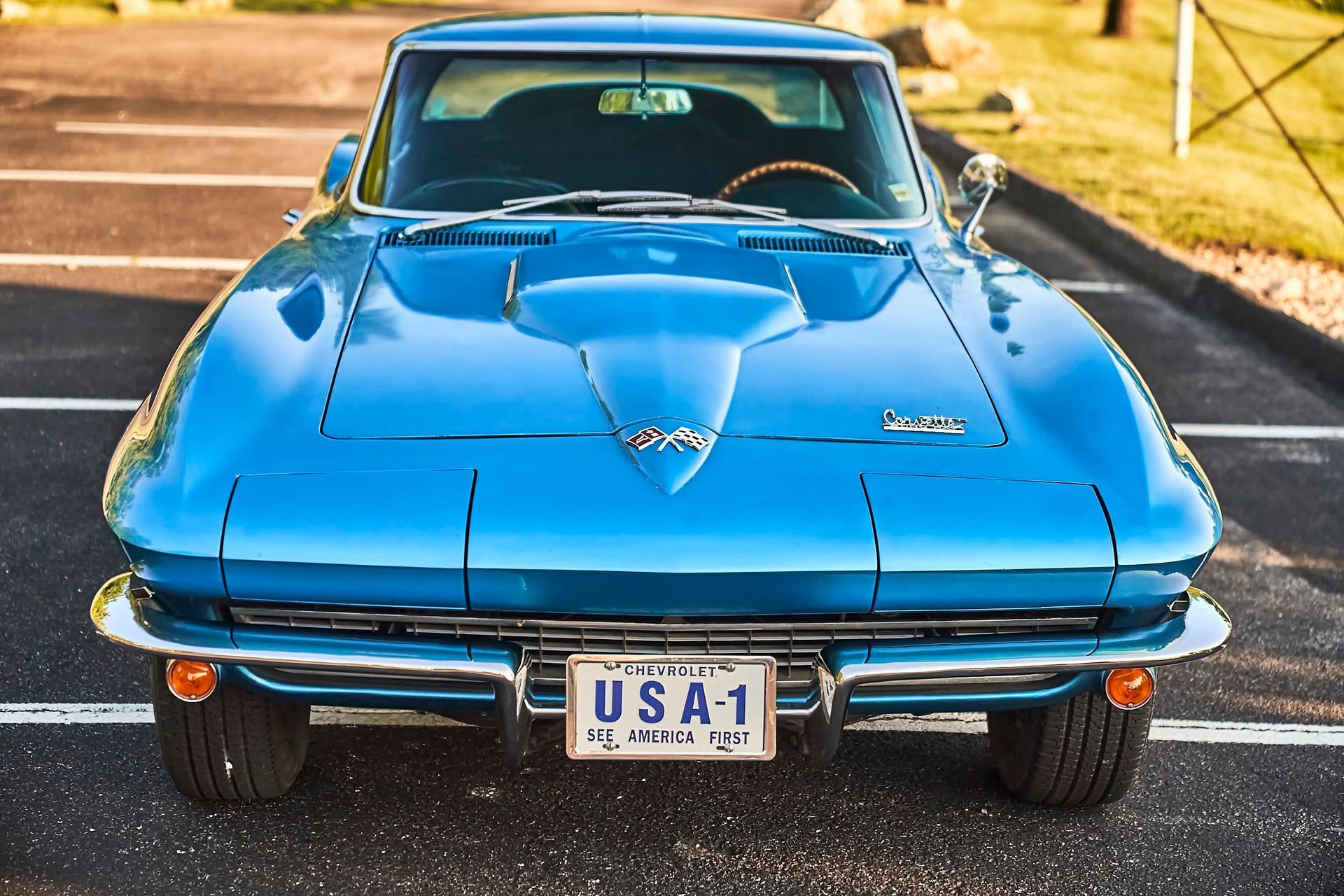Blue classic Chevrolet Corvette sports car, parked outdoors, facing the viewer.  A license plate reads 
