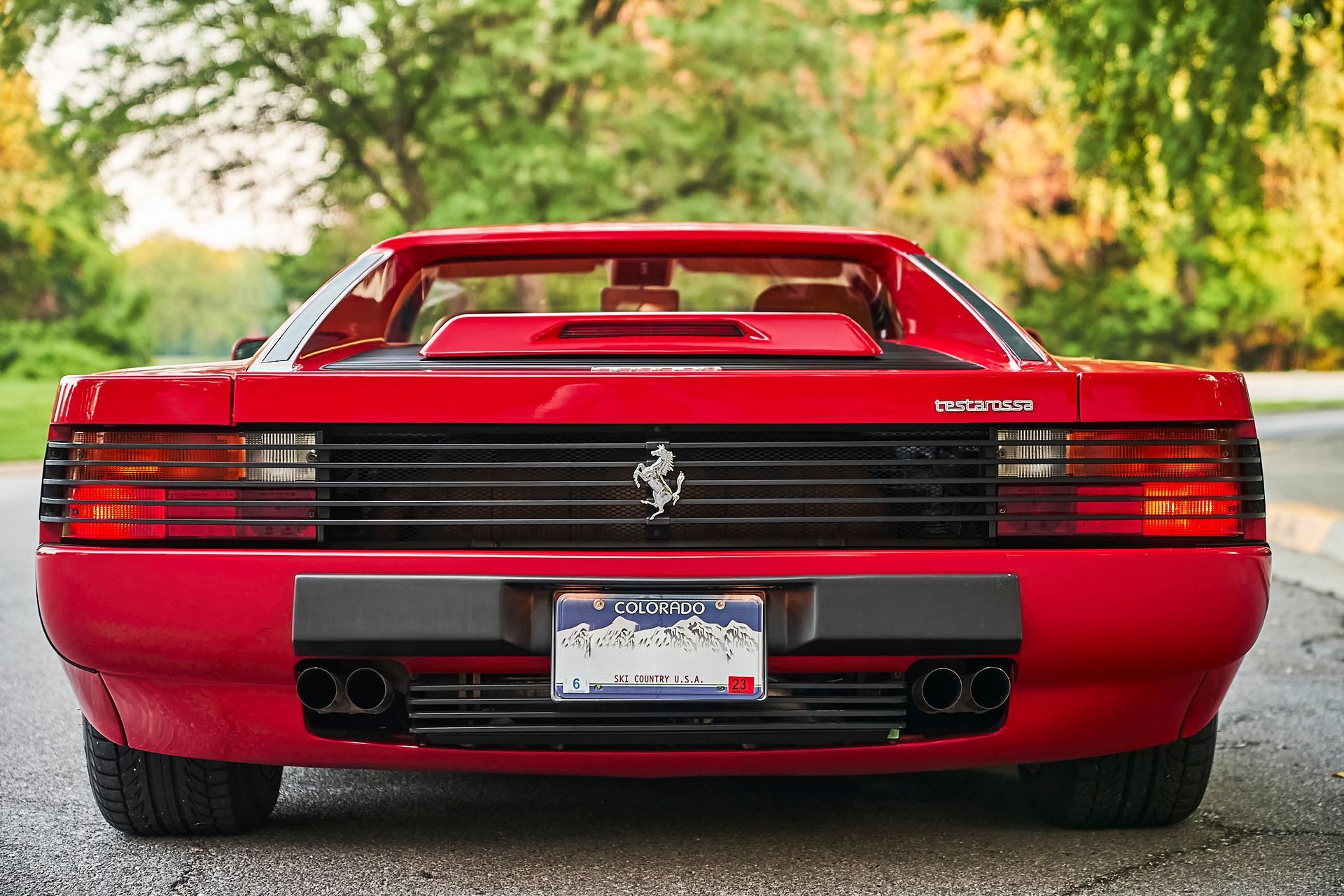 A red ferrari is parked on the side of the road.