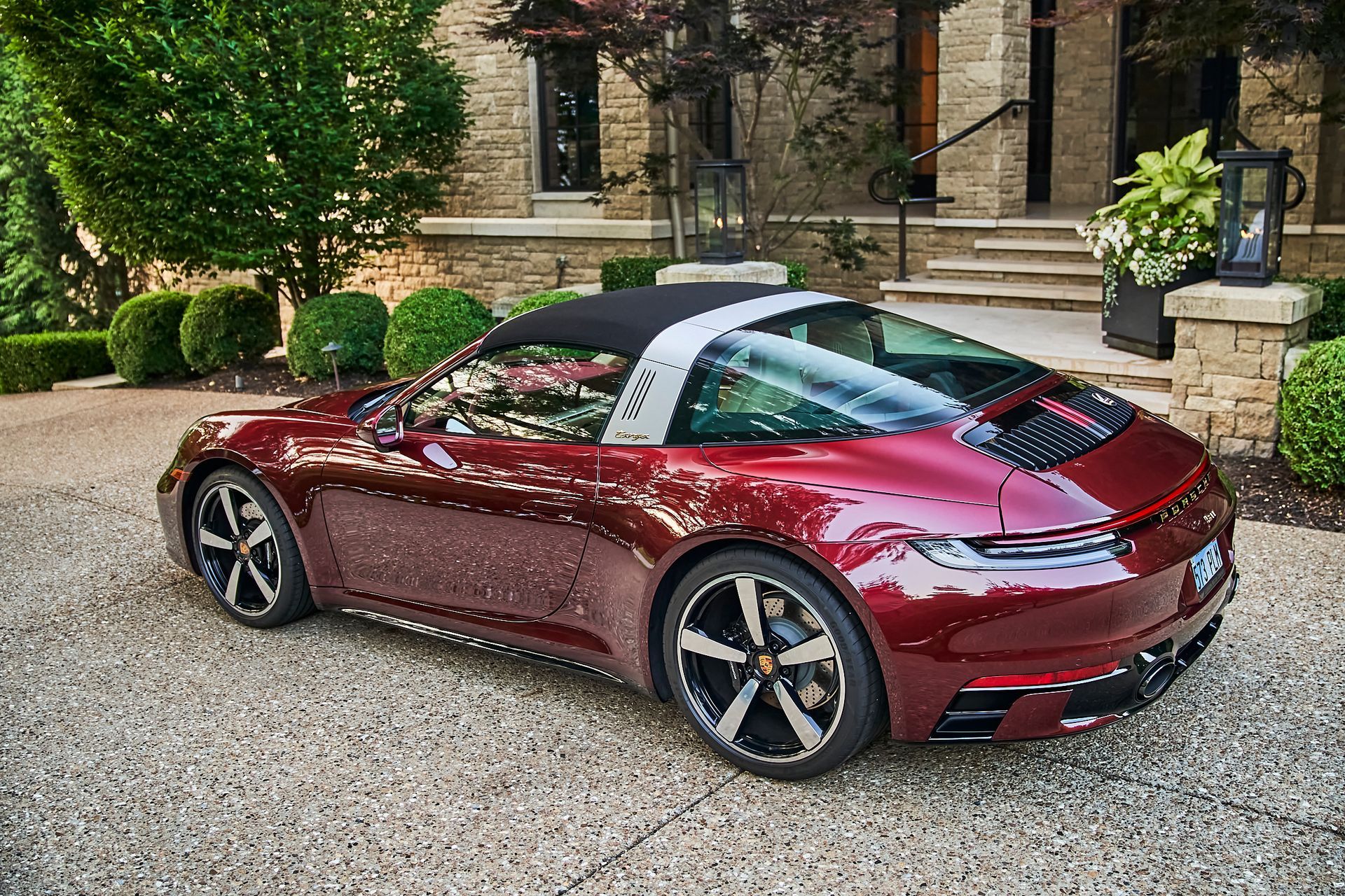 A red porsche targa is parked in a driveway in front of a house.